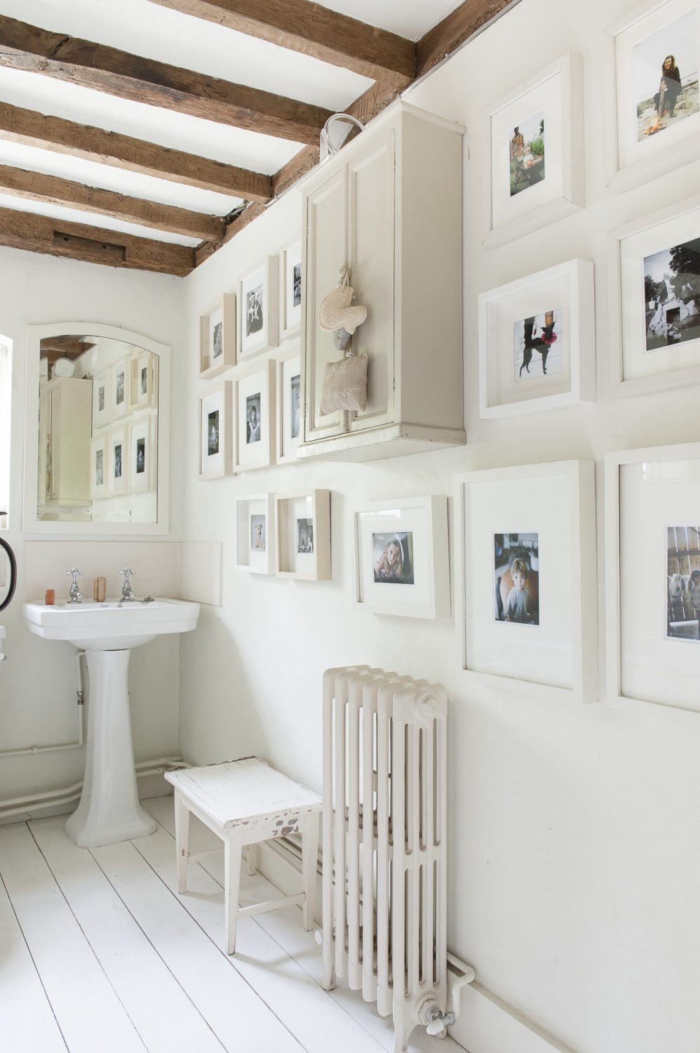 Family photographs cover the walls of the pure white bathroom