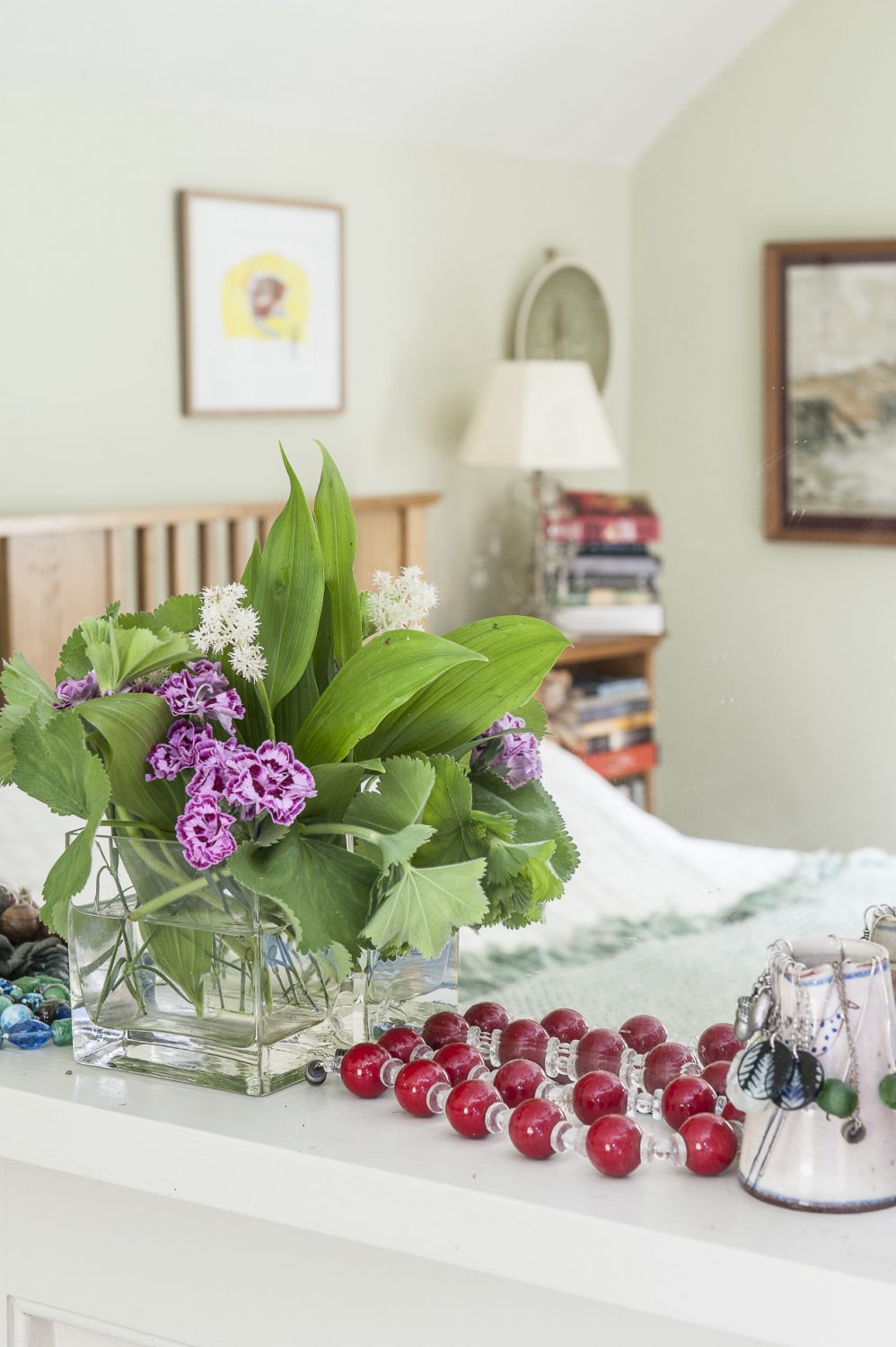 The master bedroom is painted a calming hue of very pale green. As in most rooms of the house, Wendy has gathered flowers and foliage from the garden which are positioned on the mantelpiece alongside her jewellery