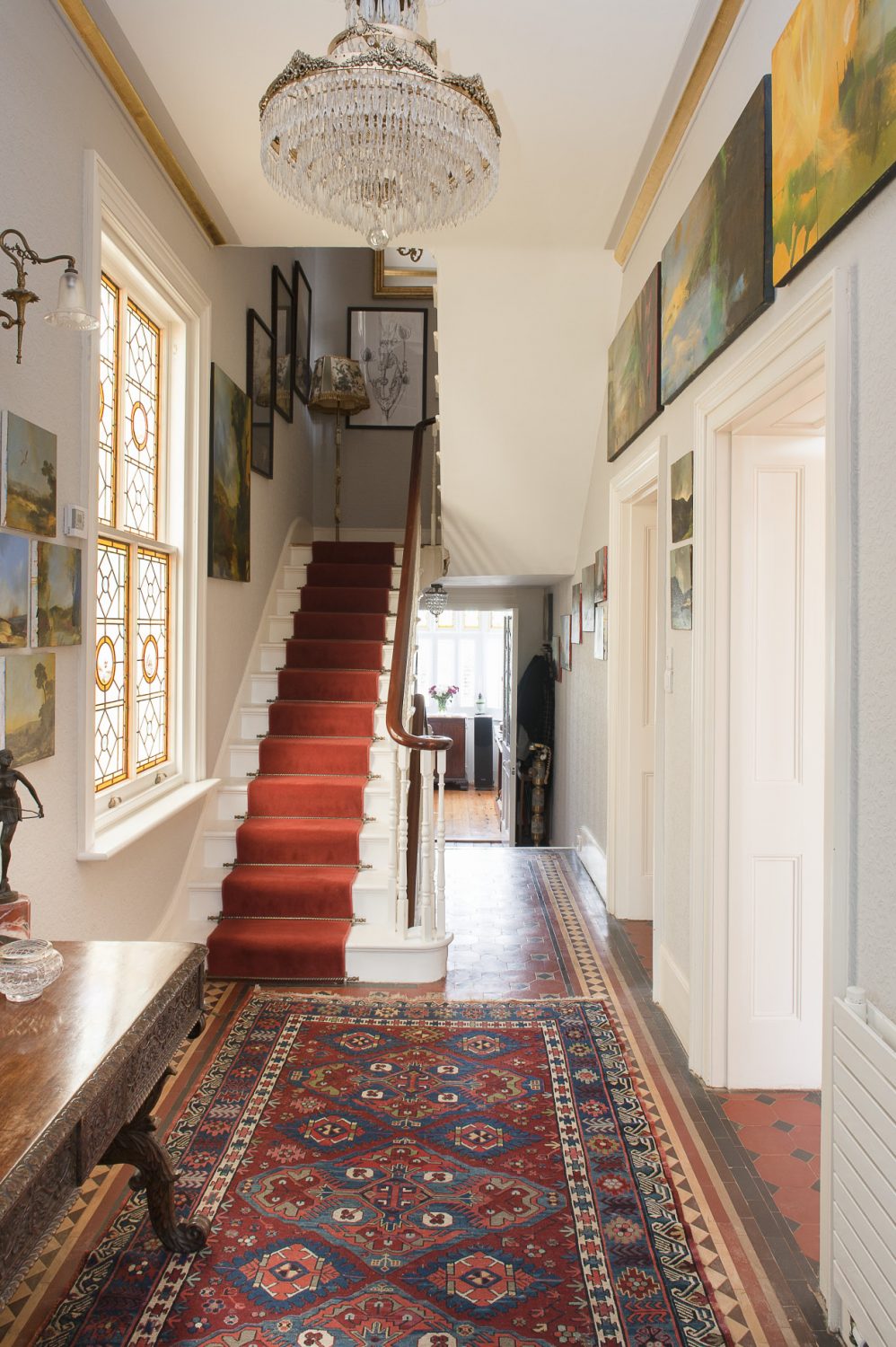 The hallway features a glowing amber stained glass window that Ken sourced in London to replace the original. Doors at the end of the hallway lead into the house’s own private chapel