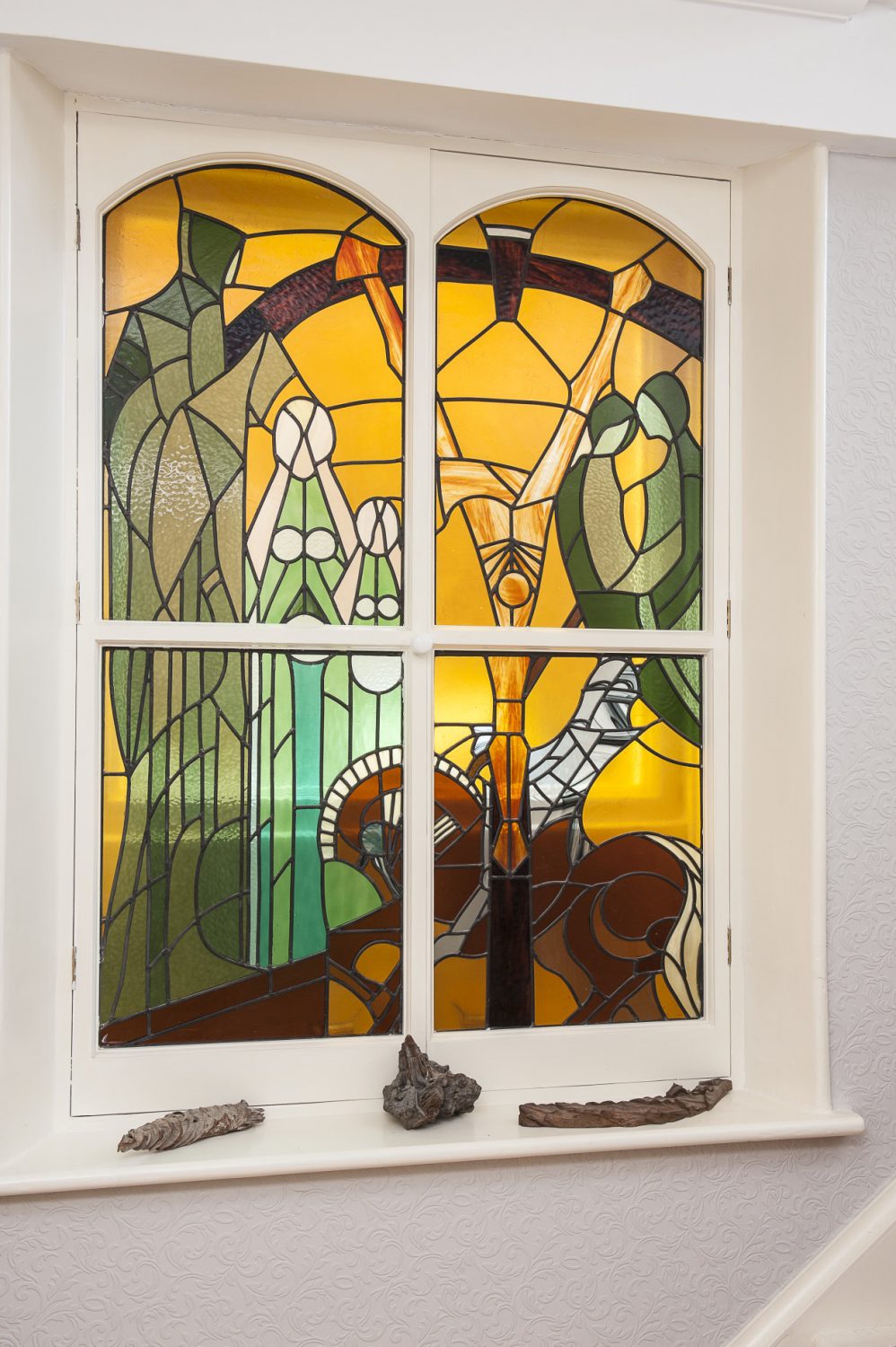 The work of Isobel Ackary is evident in the shape of two lovely stained glass-fronted cabinets and a small basement window