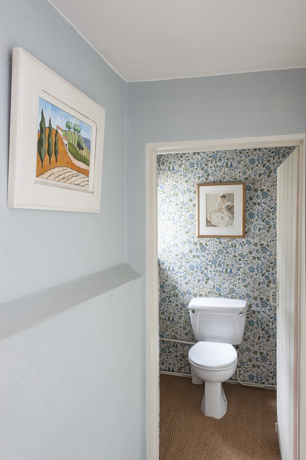 An upstairs loo remains decorated in the original blue floral wallpaper chosen by a previous owner