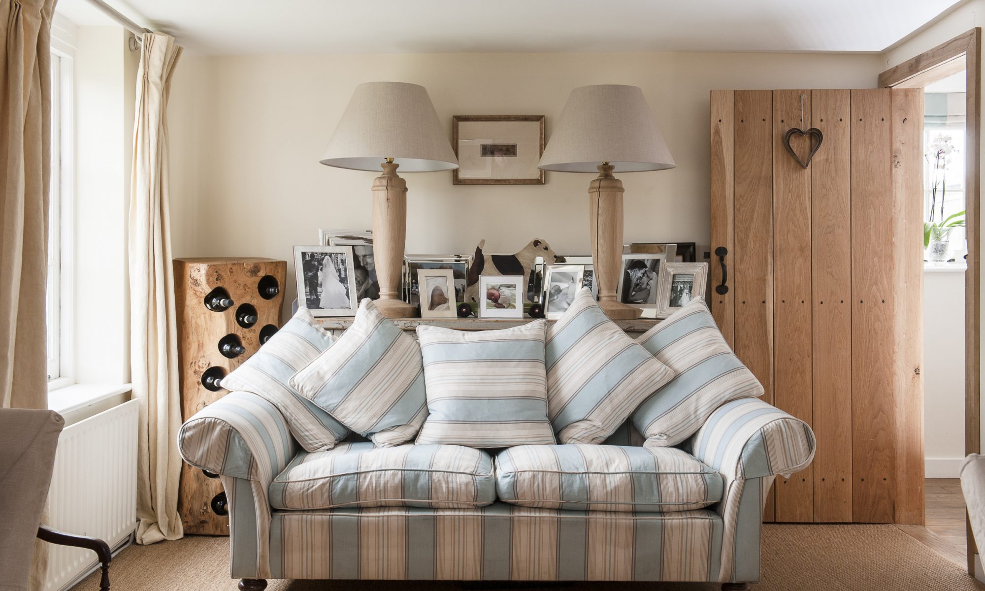 Holly found the elegant blue and white striped sofa at one end of the drawing room from Balmain & Balmain. The lamps and fox terrier toy, interspersed with groupings of family photographs, are from Holly’s company Duck & Dog