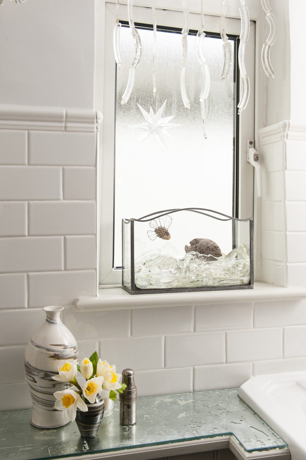 In the bathroom, Trudi has hung glass fragments in the window and created a mock aquarium using salvaged glass, crystal and a little hand-made wire and pebble fish. The off-white tiles are from Fired Earth – a more classic version of Metro tiles, but crackle glazed