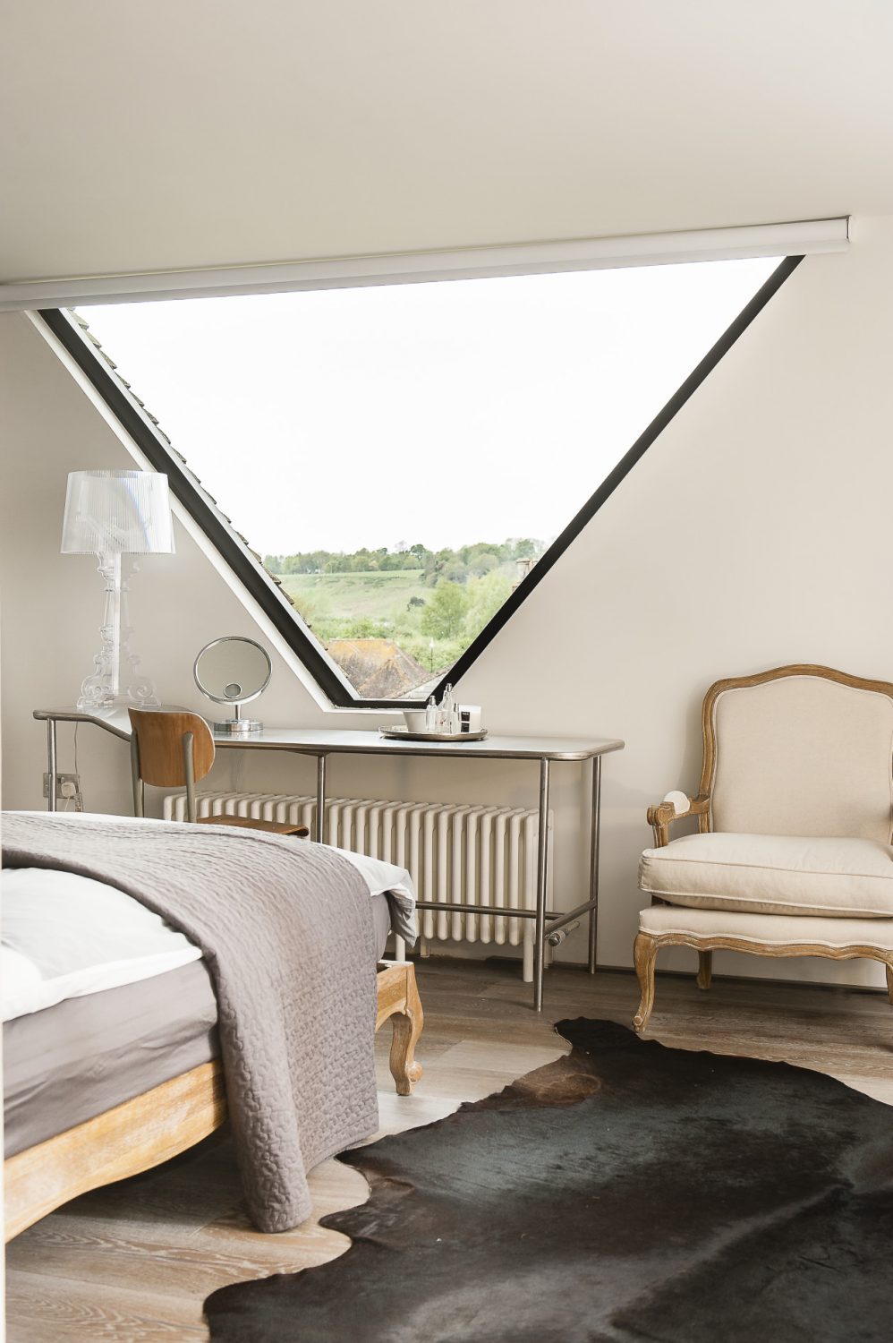 The master bedroom features an amazing triangular window that spans between the twin gables of the roof from which there are wonderful views of the surrounding buildings and the countryside beyond