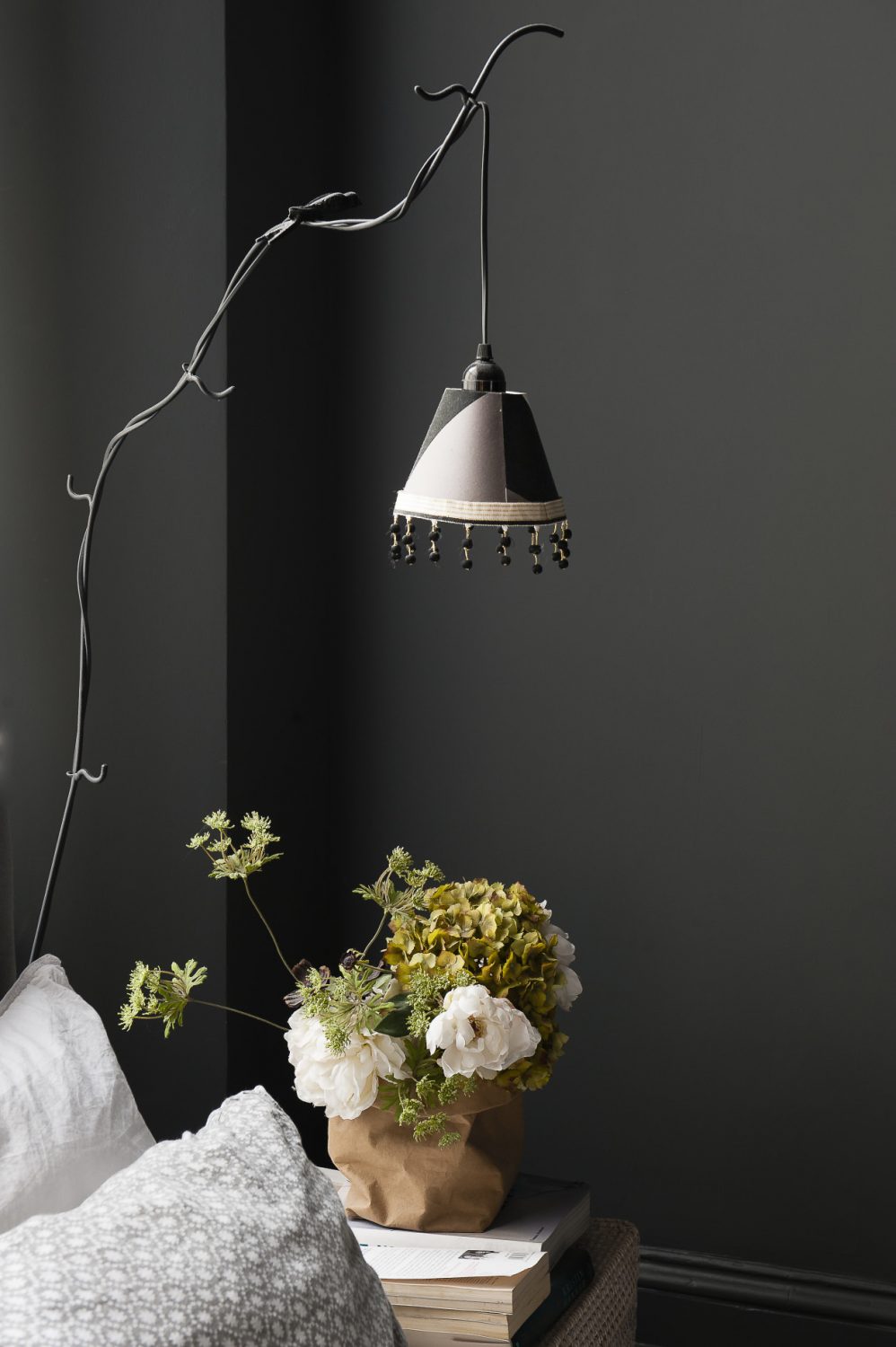 A beautiful twig-like metal floor lamp with a beaded shade acts as a bedside light