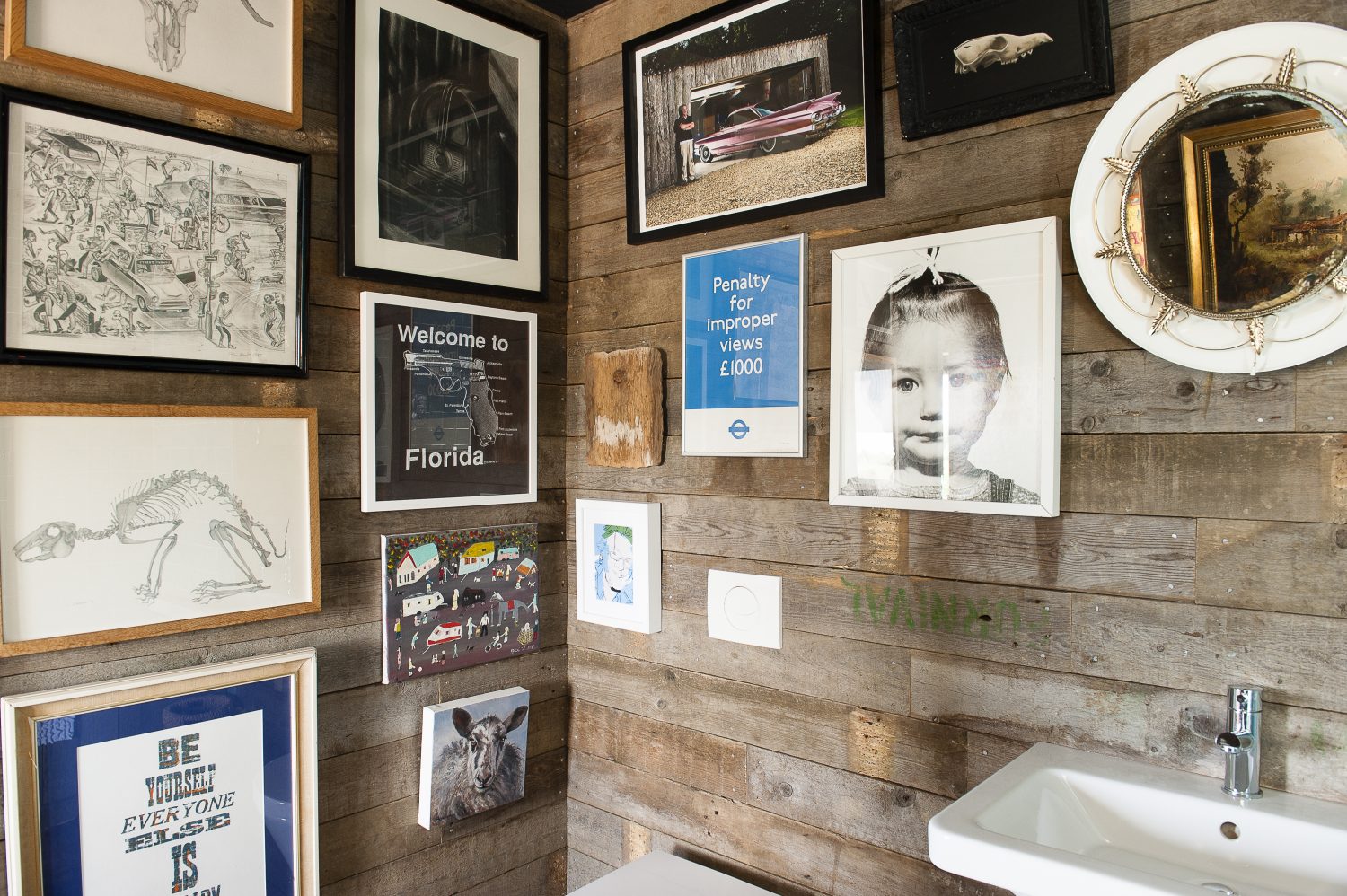 The bathroom walls are lined with an eclectic mix of artworks and photographs