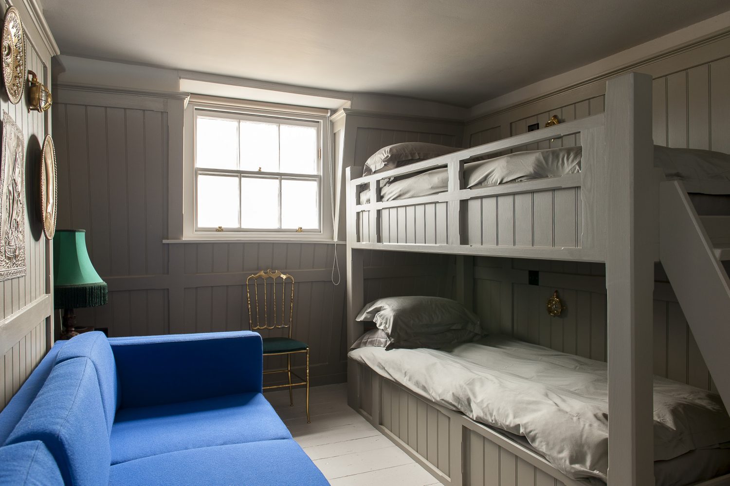 The Crow’s Nest’s bunk bed den features a wall of pressed brass plates