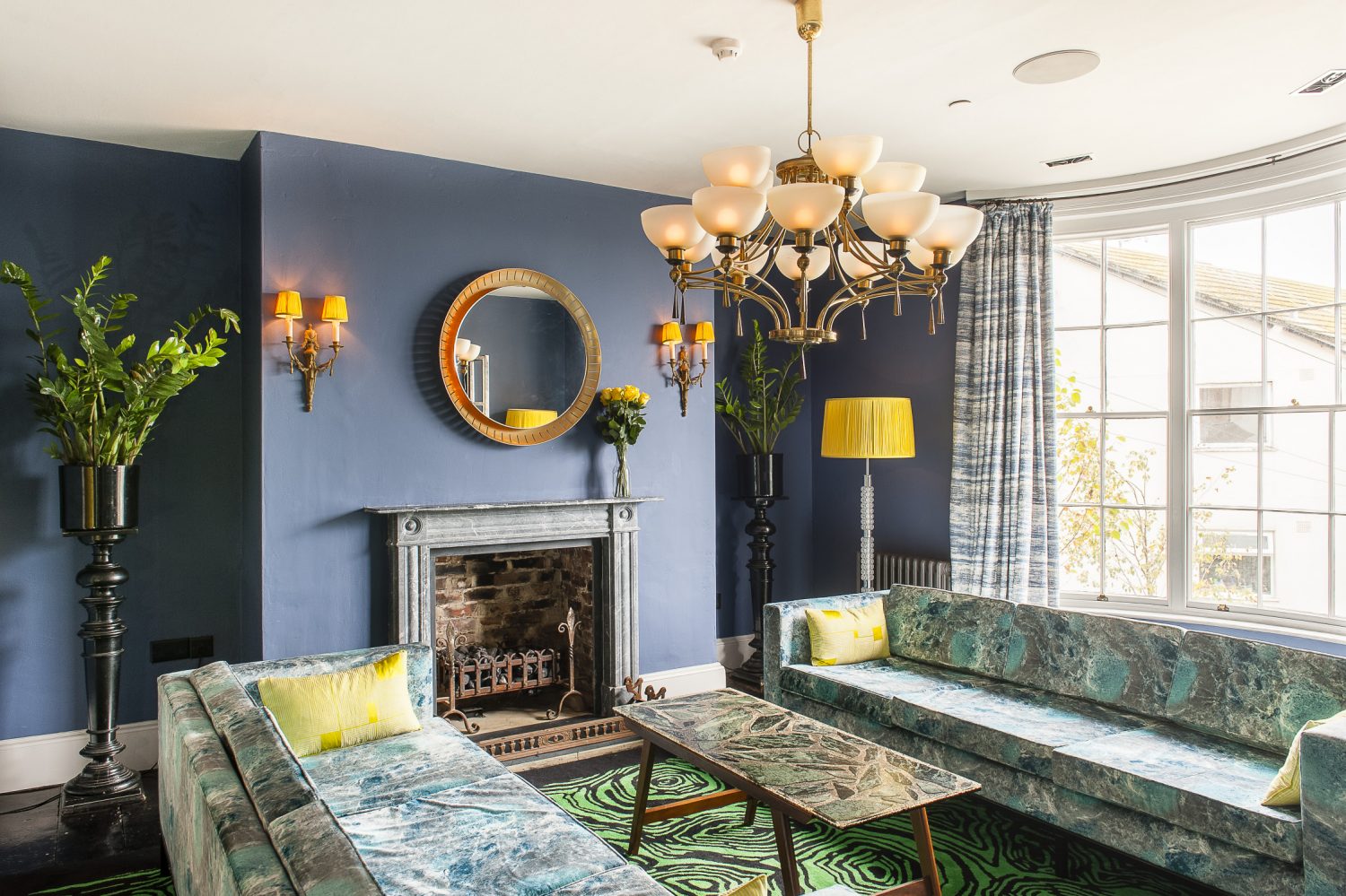 Two custom made marble-print velvet sofas sit below a 1940s brass chandelier in the sitting room
