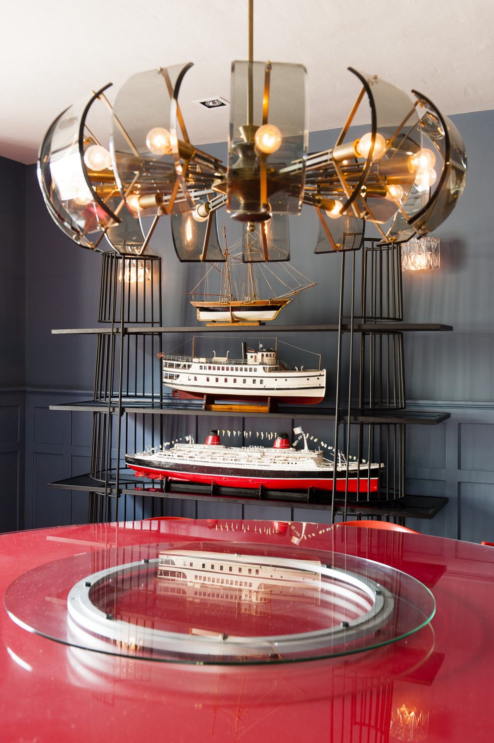 The dining room can seat ten around a huge round red table. 1950s metal and wood bookshelves display three large model boats from Ardingly, while opposite, glass-fronted original cupboards on either side of the fireplace display musters of stoneware, cabbage ware, pewter, silver and crystal