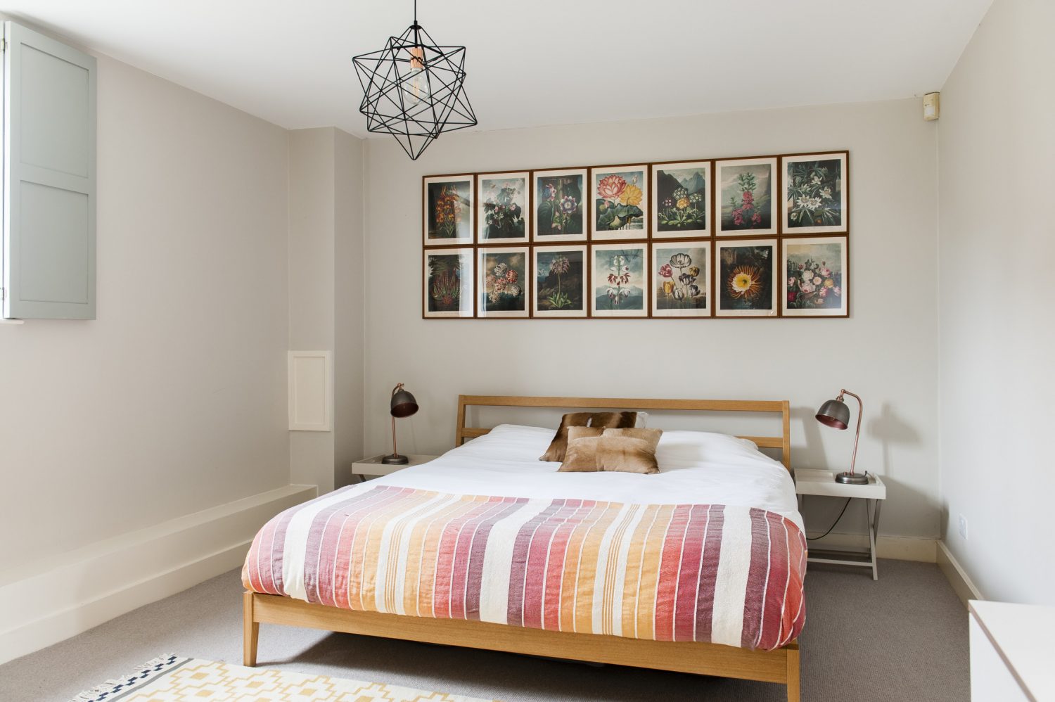 Another door from the dining area leads through to a generously sized bedroom, painted in Farrow & Ball Skimming Stone. A striking arrangement of framed flower prints hang over the headboard, taken from a book called the The Temple of Flora by a botanist Robert John Thornton