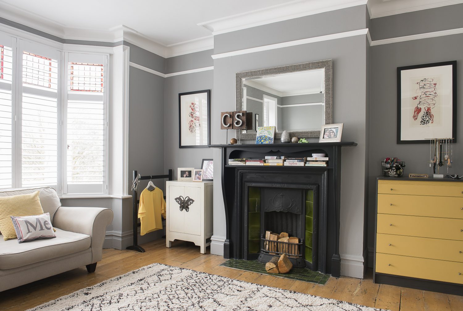 A brightly painted chest of drawers contrasts with the cool greys and blacks of the master bedroom