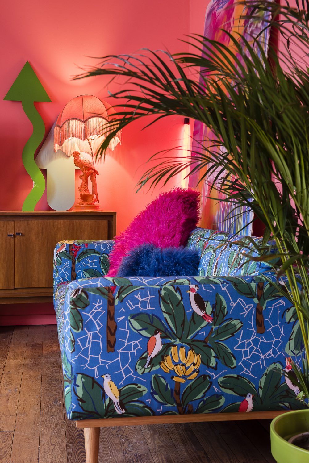 Tropical birds and foliage feature on the upholstery of another sofa, alongside a neon light and a large spray-painted canvas which rests against one wall