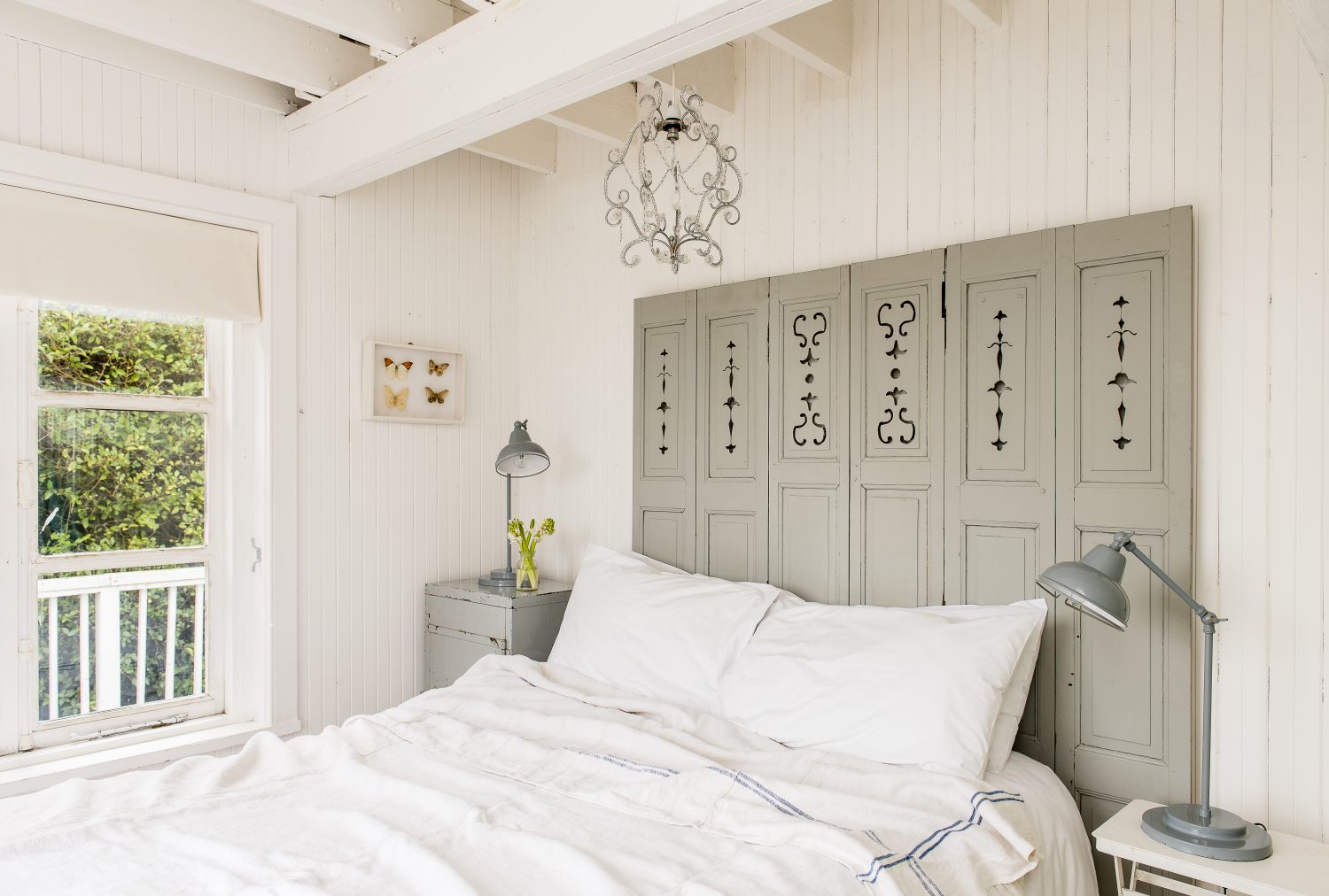 The headboard is made from old shutters painted with Farrow & Ball’s Lamp Room Gray. The bedside lamps are from Pale & Interesting