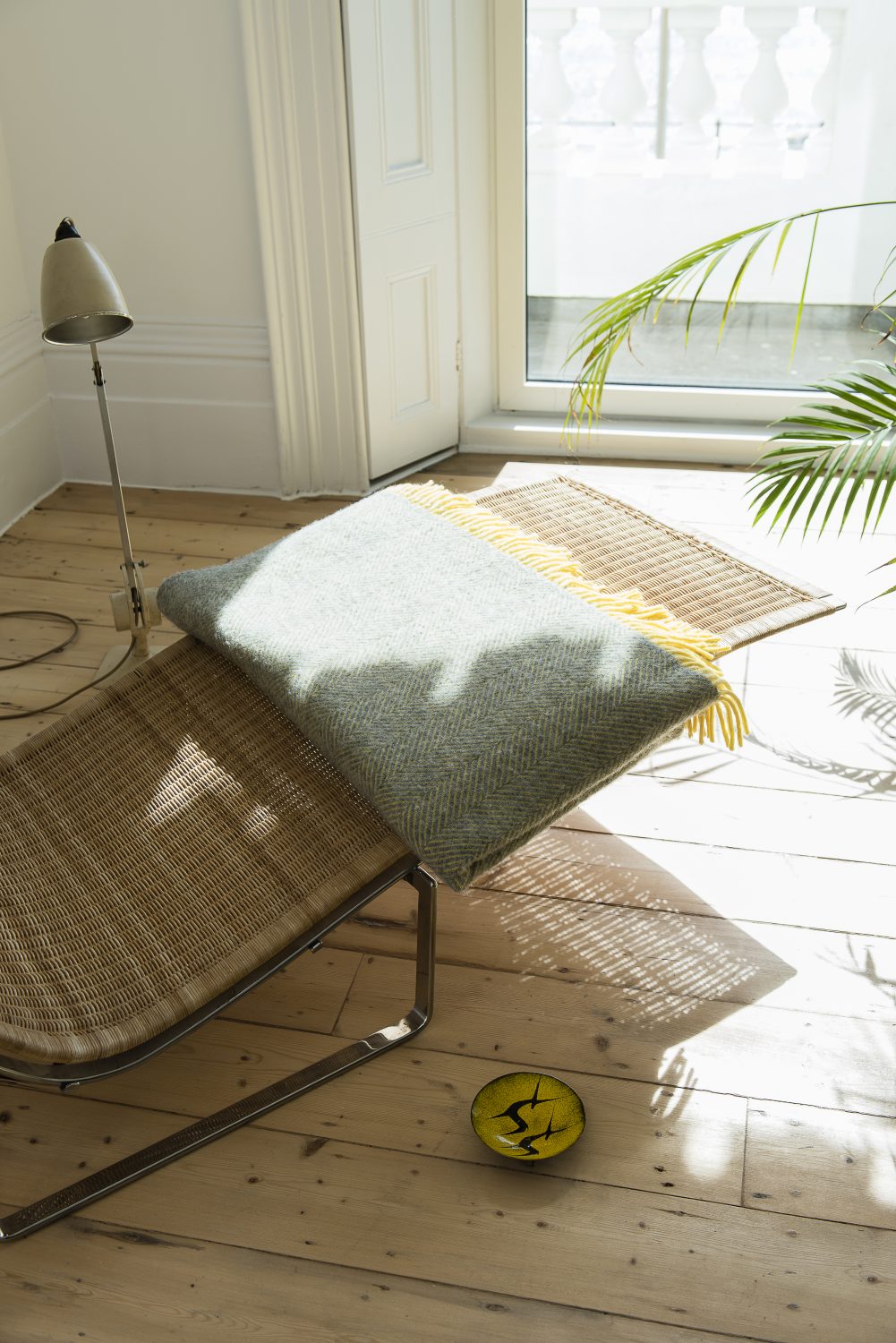 The main living area has floor-length windows with views out to sea. The rattan chaise longue is by Poul Kjaerholm