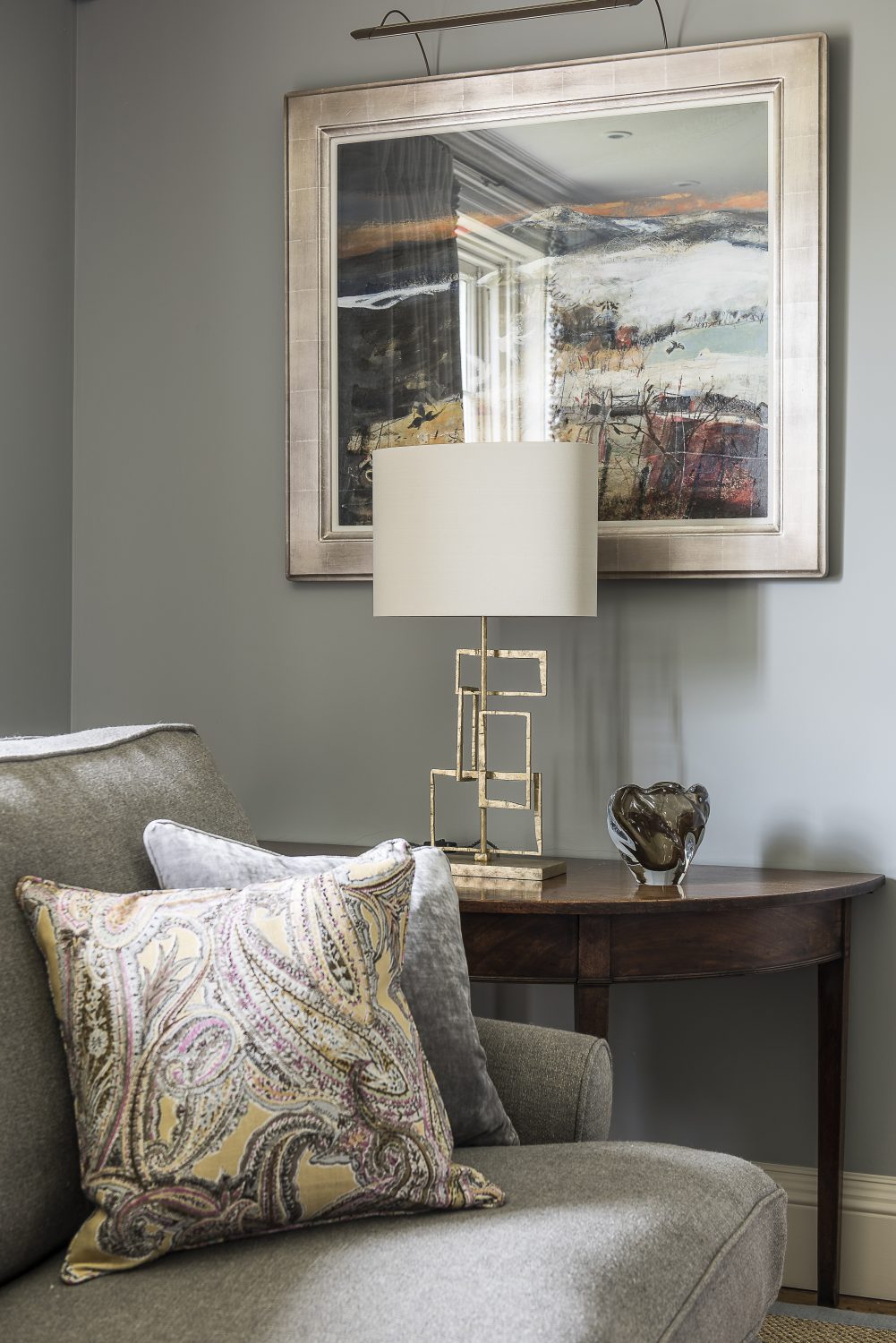 More bookshelves in the drawing room. The oversized ottoman is upholstered in a William Yerwood jute stripe. The patterned cushions are a Nina Campbell linen. The brass lamp is by Porto Romana. The painting client’s own