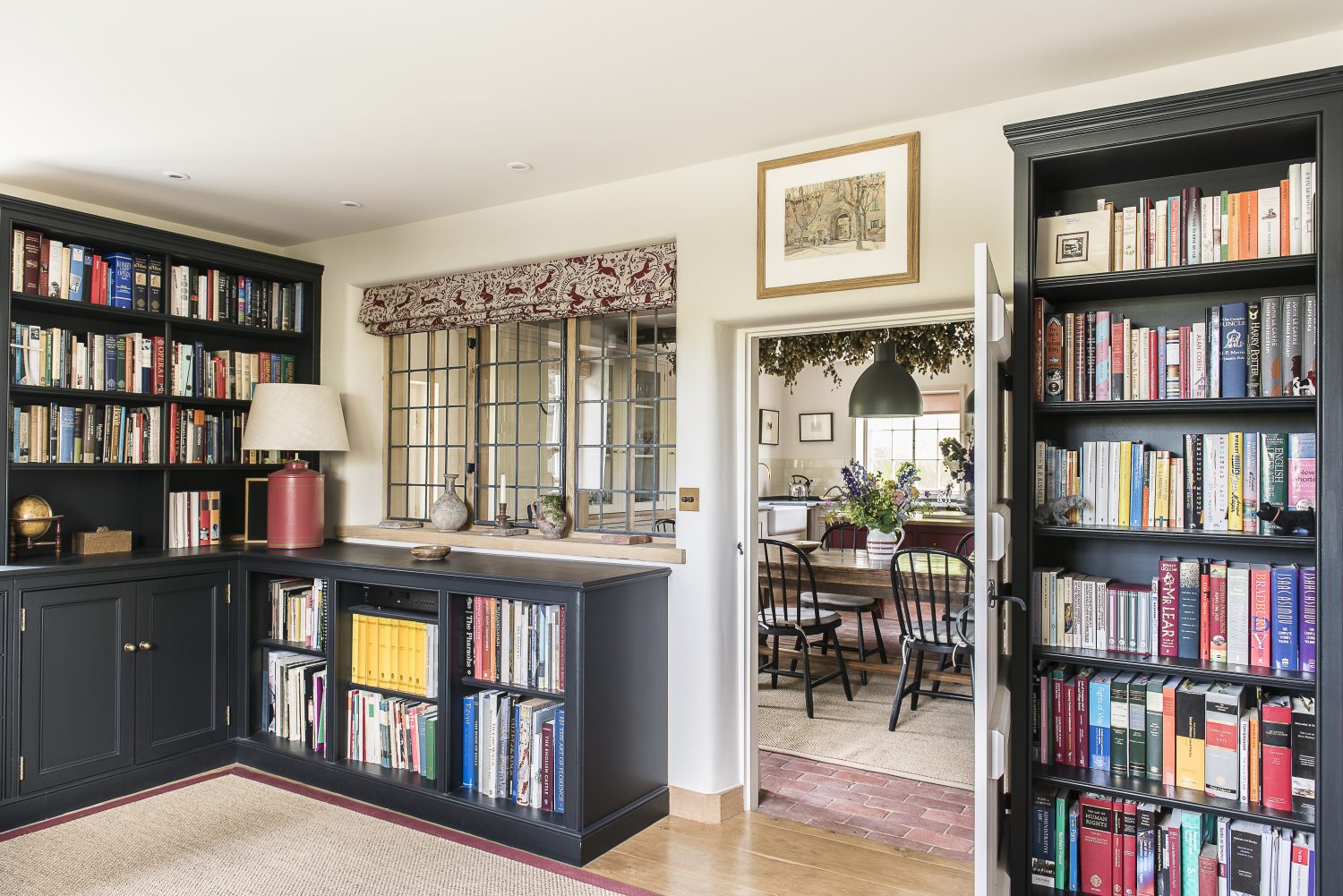 The book-lined study leads into the kitchen. The blind fabric was designed by Lindsay Alker