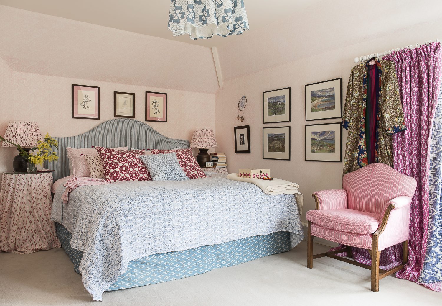 In the master bedroom, all the fabrics – quilt, headboard, lampshades, valance, bedding, cushions, chair – and the wallpaper are all from Molly Mahon