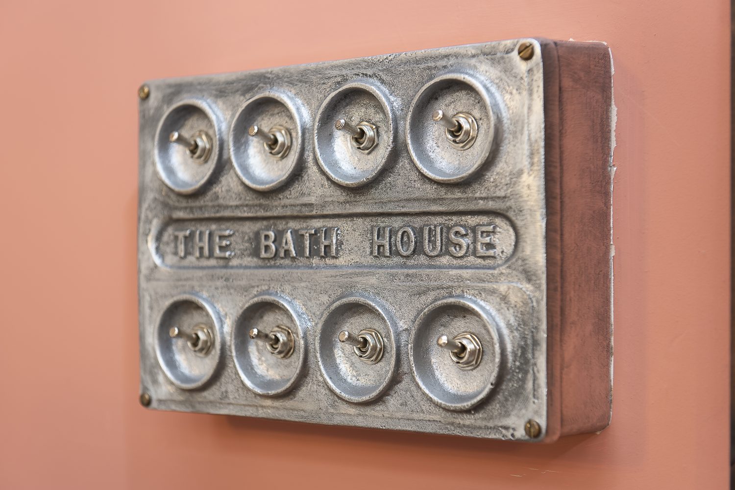 Bespoke industrial steel light switches and plug points are embossed with the words The Bath House