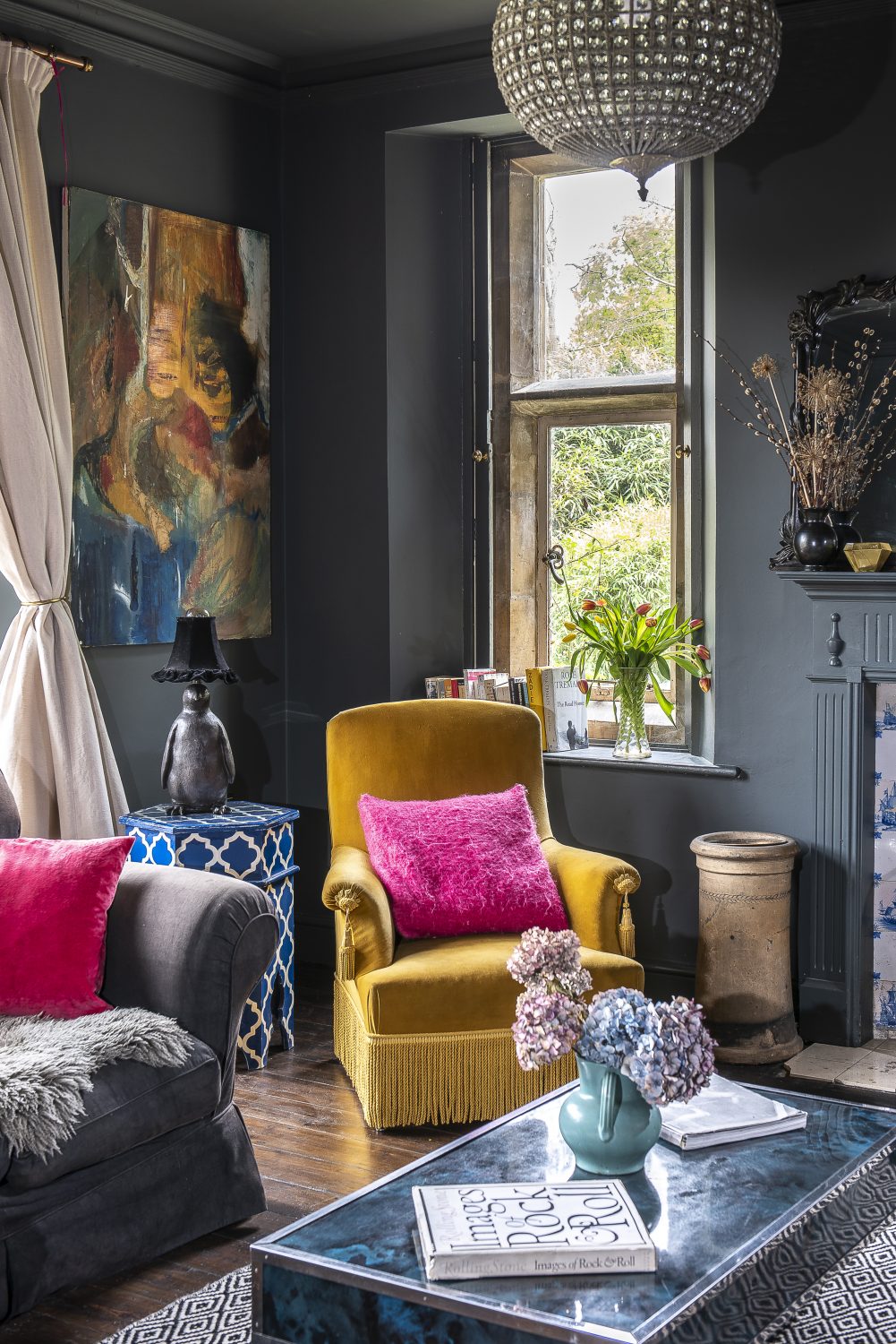 A cosy sitting room, used as a games room, features the original Delft tiles around the fireplace and stone-mullioned windows; opposite the fireplace, a refectory table provides the perfect place to set up a Monopoly board