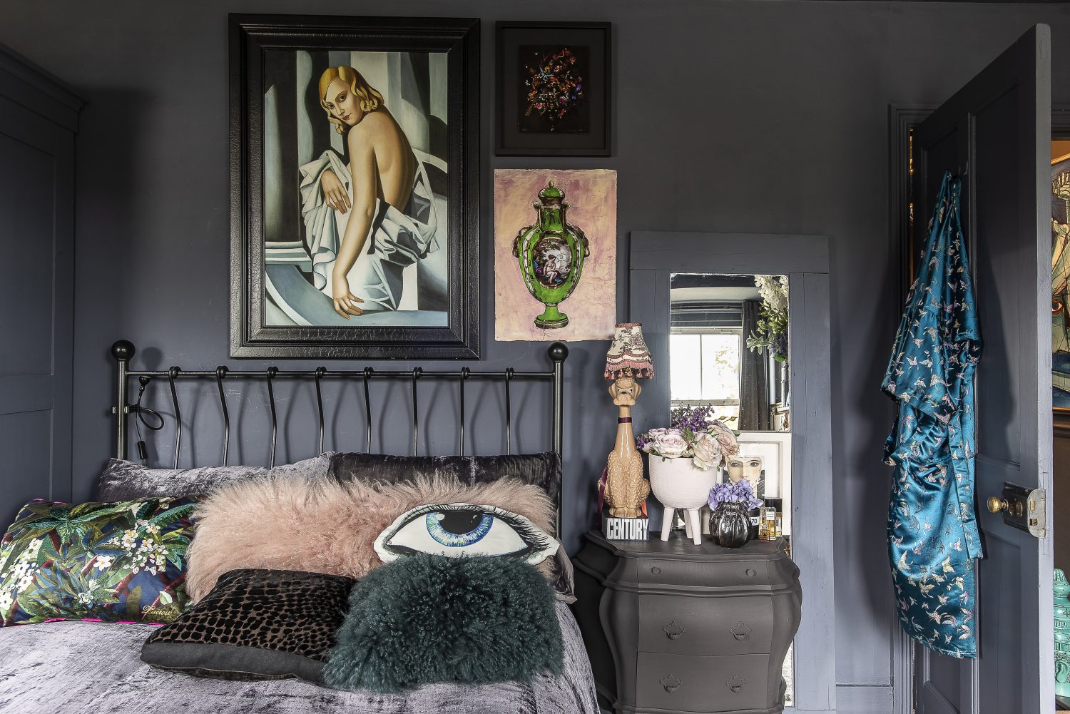 Pinks, greens and blues picked out in the artworks are matched by soft furnishings. Wallpaper printed with ornate panelling on one wall by Rockett St George breaks up the deep grey used to paint the walls, ceiling, wardrobe and door giving an illusion of ‘relief’