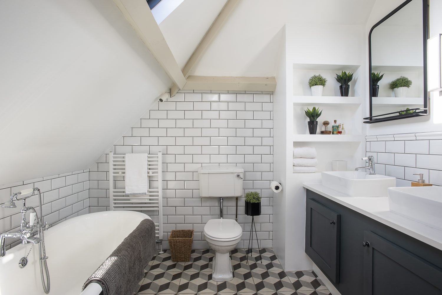 The master bathroom features beautiful geometric floor tiles that complement the matte black roll-top bath