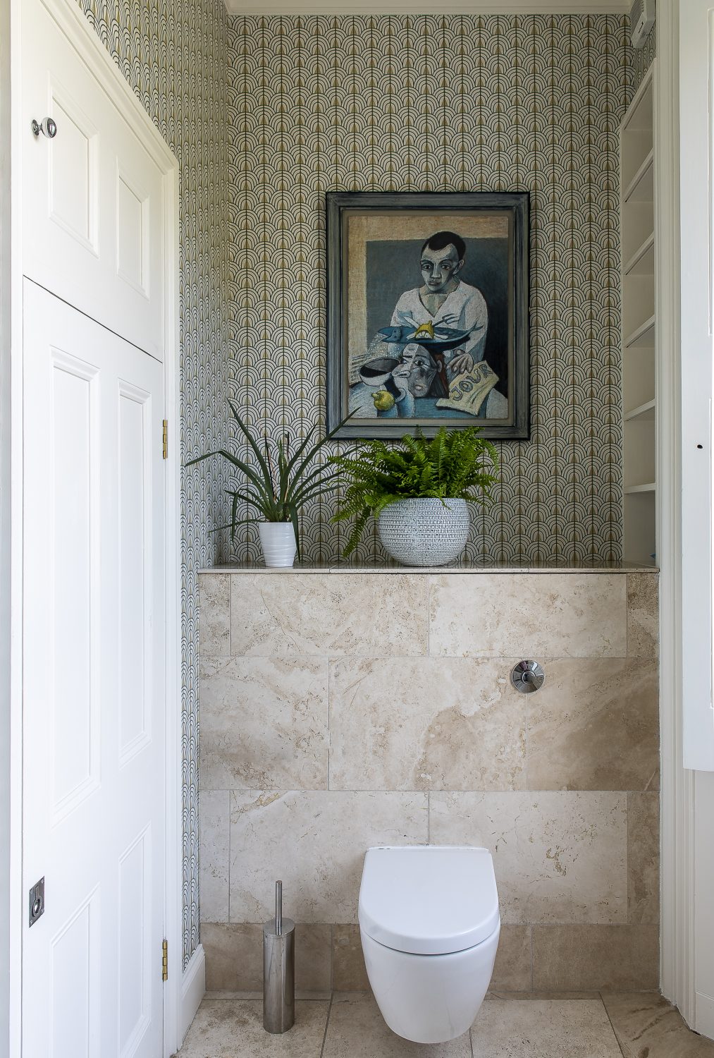 The downstairs loo has been decorated in a stylish contemporary geometric printed wallpaper. A bookcase is packed with Penguin classics, which Olya sourced from eBay. The marble sink is flanked by two wheatsheaf lighting sconces that sit either side of an antique mirror