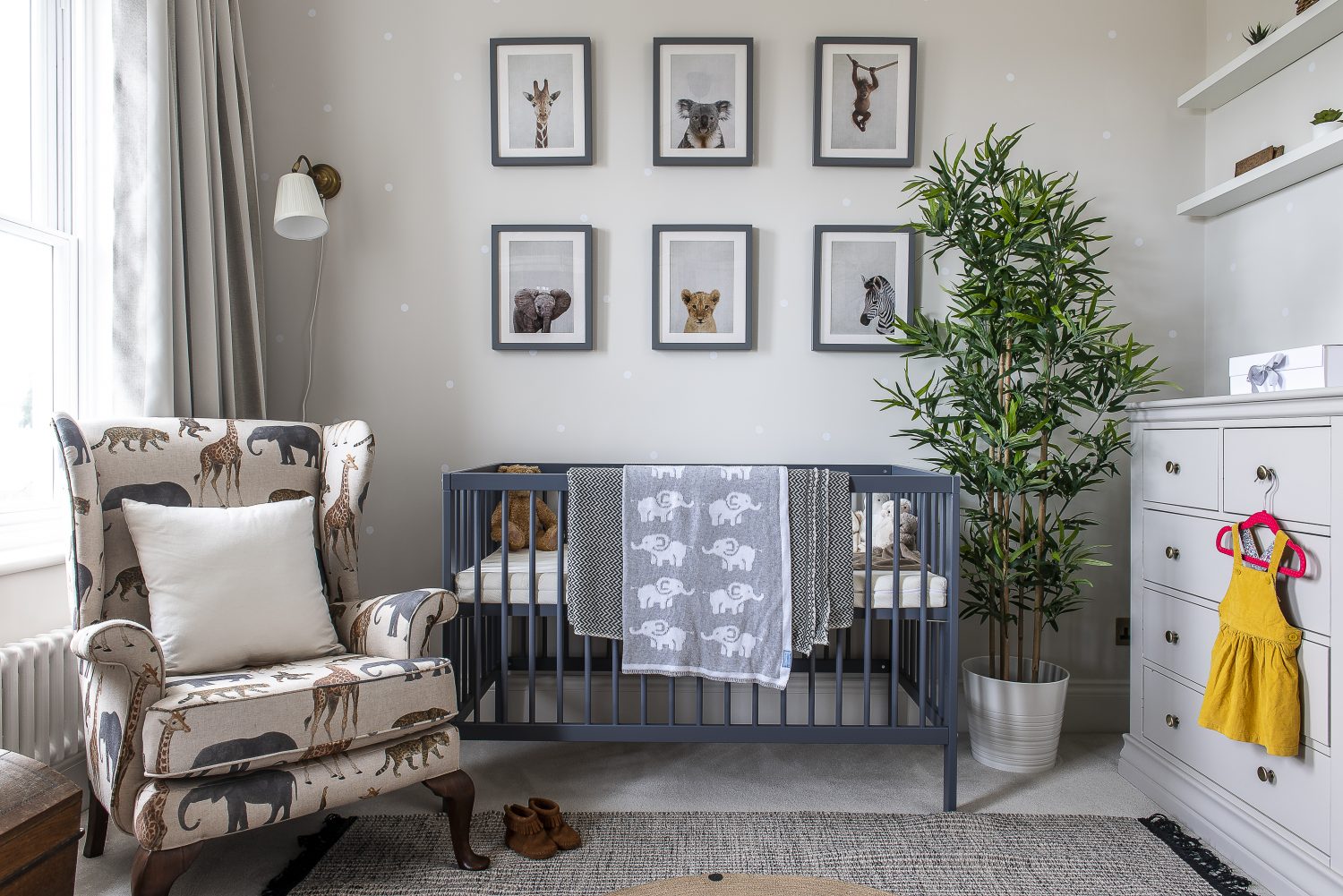 The nursery wallpaper features subtle polka dots on a soft grey background. Zoe had the chair reupholstered in African animal fabric