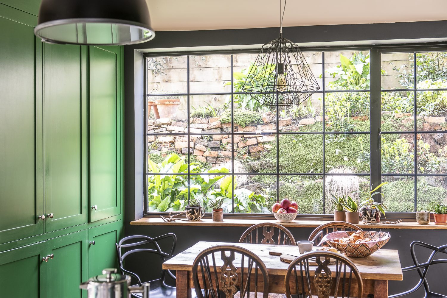 The cabinet work and cupboards in the kitchen have all been painted in a bright grass green, Sadie’s favourite colour, with black accent walls around the range cooker and the picture window