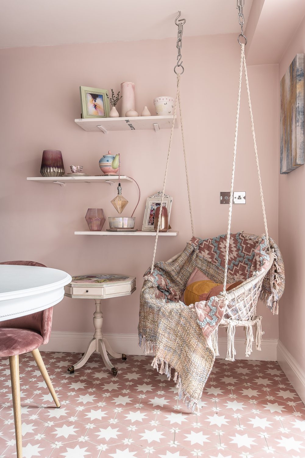 A cosy macrame-style swinging chair is adorned with blankets and suspended from the ceiling in the dining room