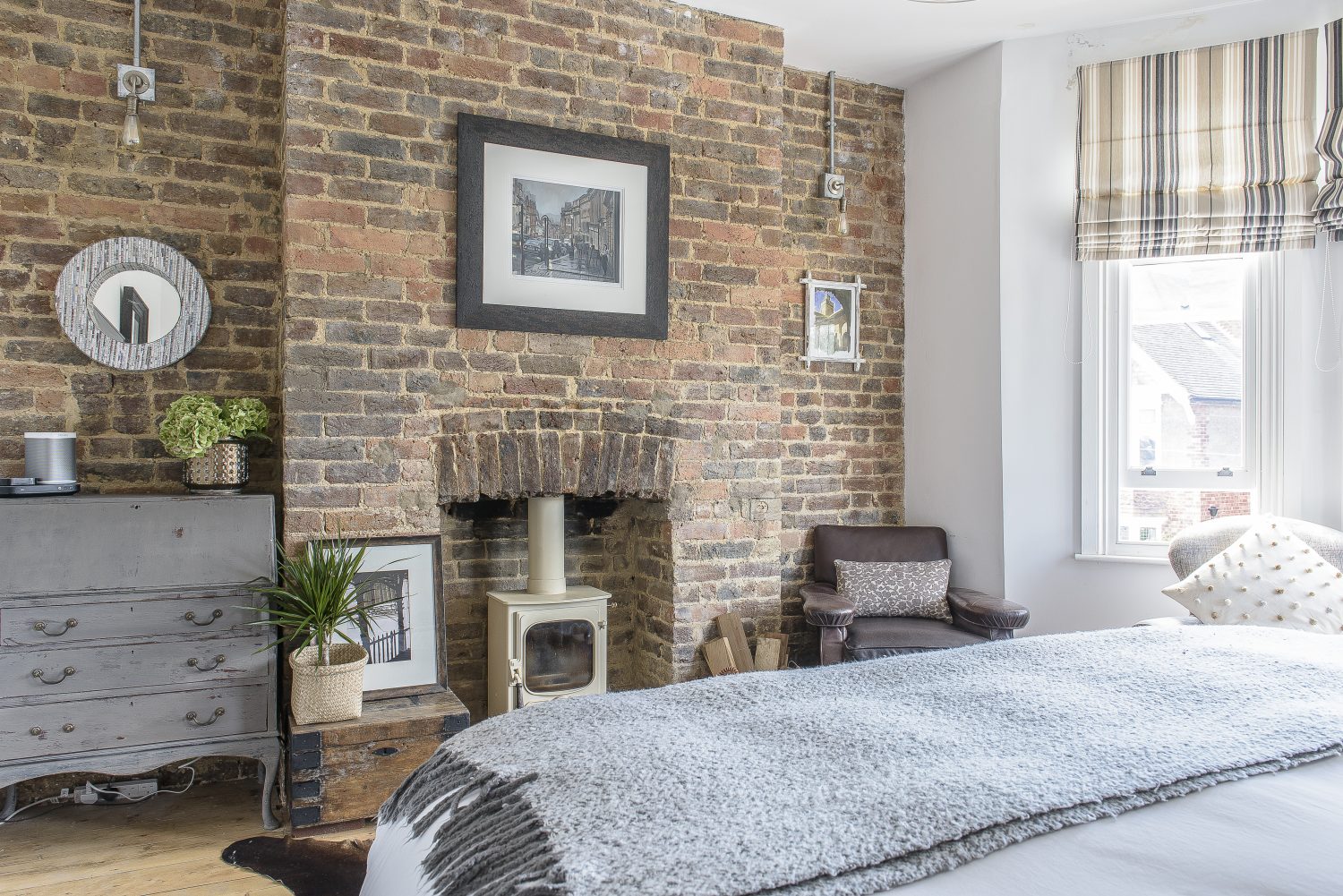 The whole first floor has been created as a master suite, with the bedroom styled as a cosy second sitting room, with a woodburner, against another wall of exposed brick