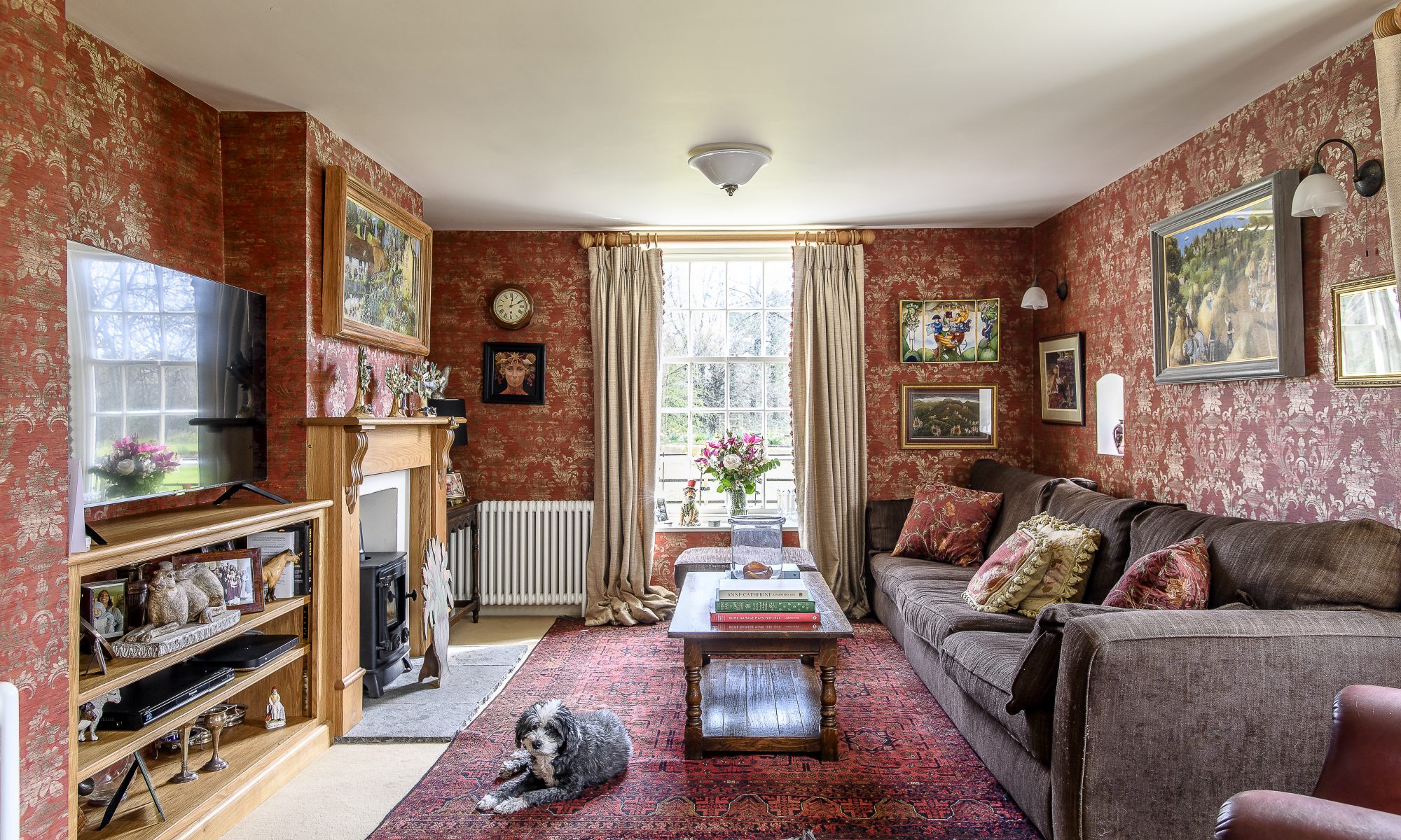 The sitting room exudes warmth and comfort with a palette of rich reds and squashy sofas