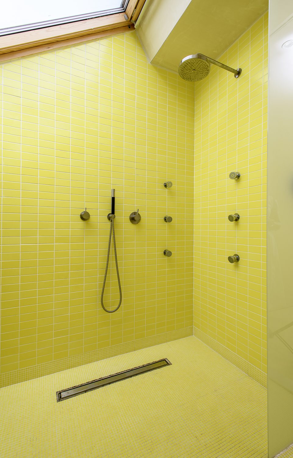 A shower area tiled entirely in yellow