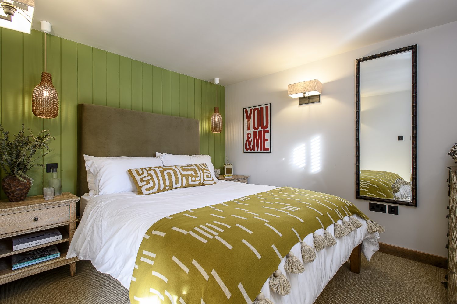 The simply furnished bedroom is set off by a panelled back wall and a bespoke headboard designed by Ben