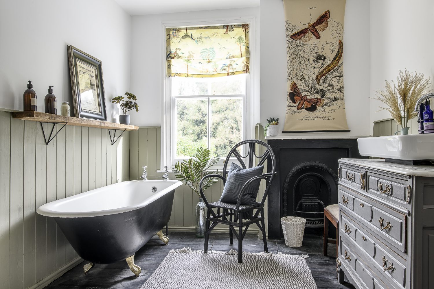 The family bathroom features another freestanding bath, this time in black with gold claw feet – a pleasing contrast to the pale sage green panelling and in keeping with the original cast iron fireplace