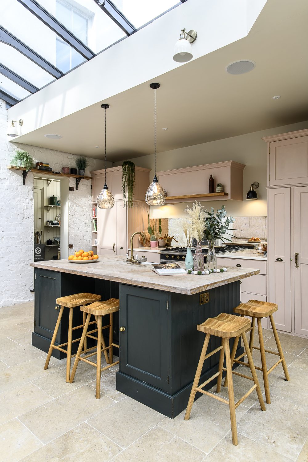 The kitchen has the feel of an orangery, occupying the width of the house, with a generous island unit, underfloor heating and a hardwearing La Rochelle limestone, a pale natural stone that enhances the bright airiness of the room 
