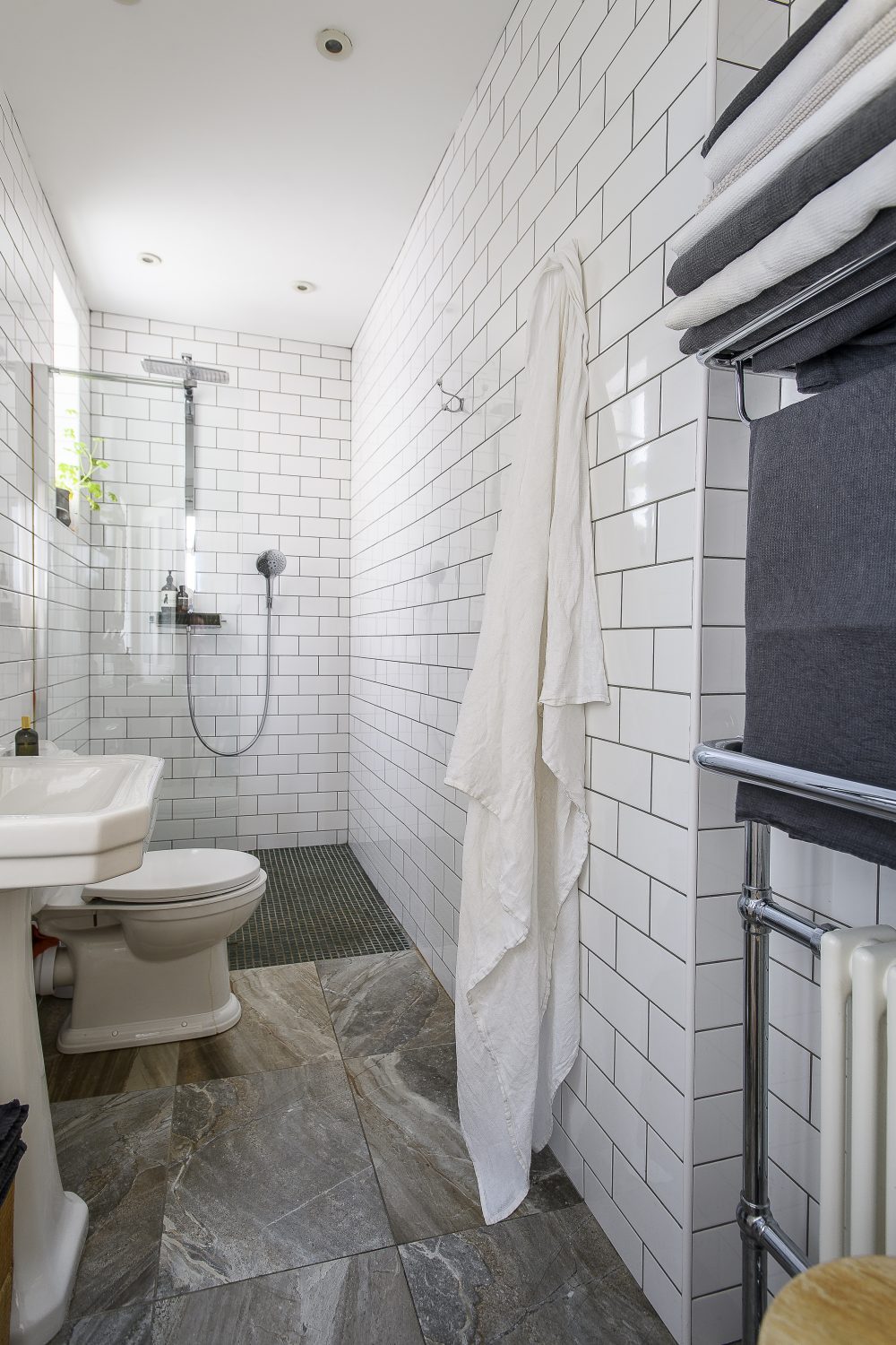 Pristine tiles with black grout stretch floor-to-ceiling in the bathroom;