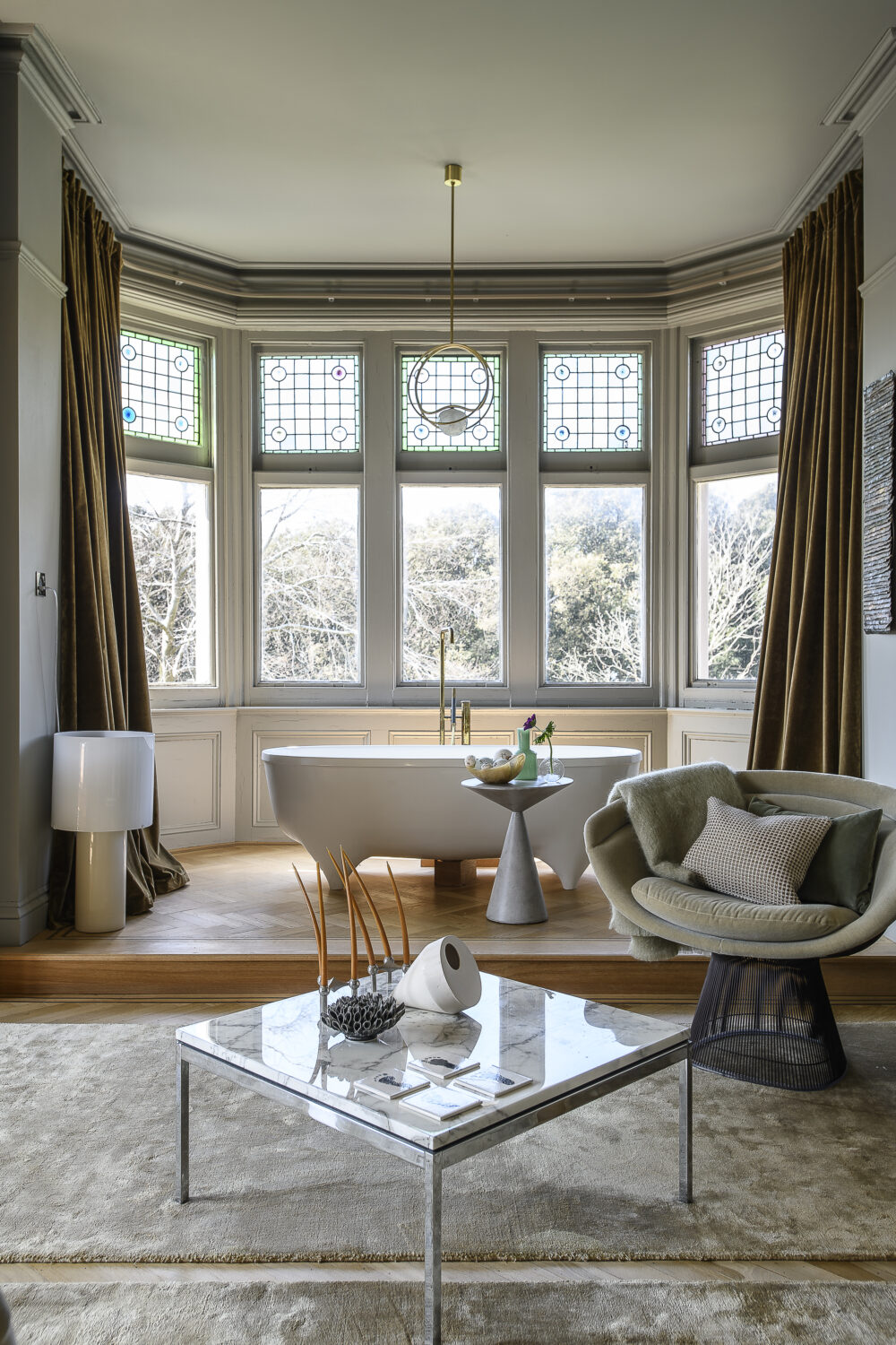 A sculptural freestanding bath, nestled within a spacious bay, overlooks the gardens outside