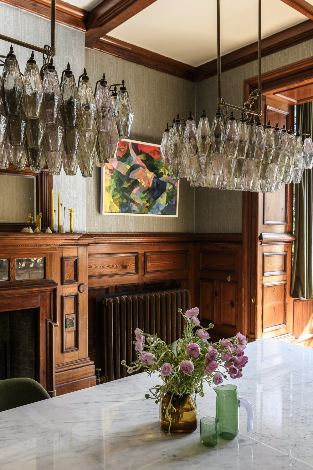 Murano glass chandeliers in the more formal of the two dining rooms draw the gaze down towards the dining table in order to bring intimacy to the room’s large proportions, creating a welcoming space for both long dinners and lively family meals