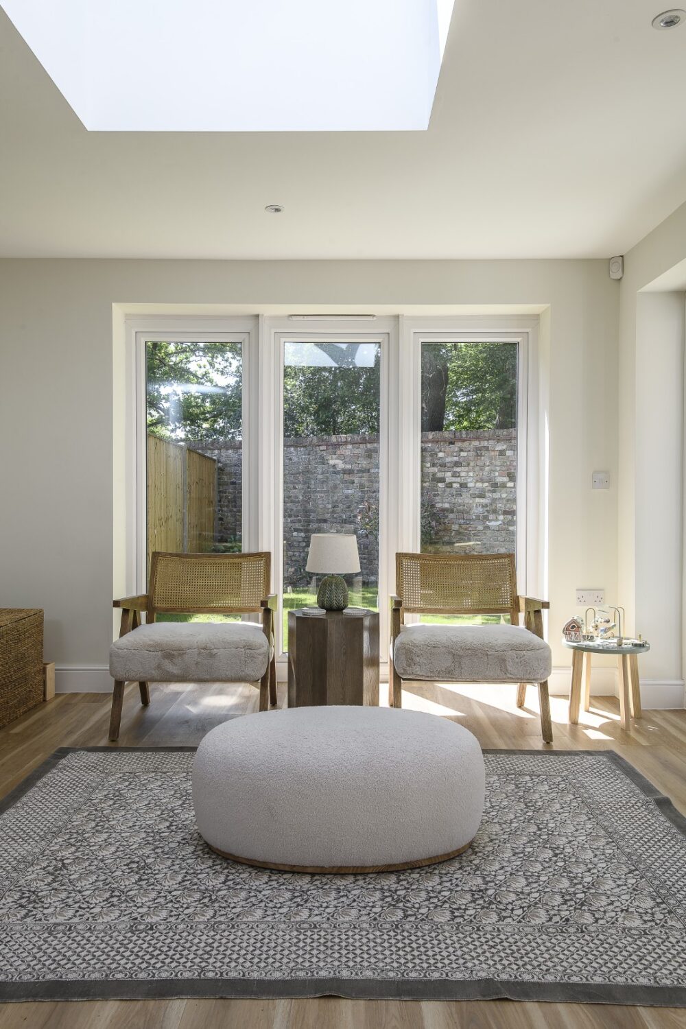 The snug space is further divided from the rest of the room by panelling on the wall and cleverly arranged furniture, including a rug from Zara Home, a forest green sofa and two chairs with the seats upholstered in a faux fur fabric