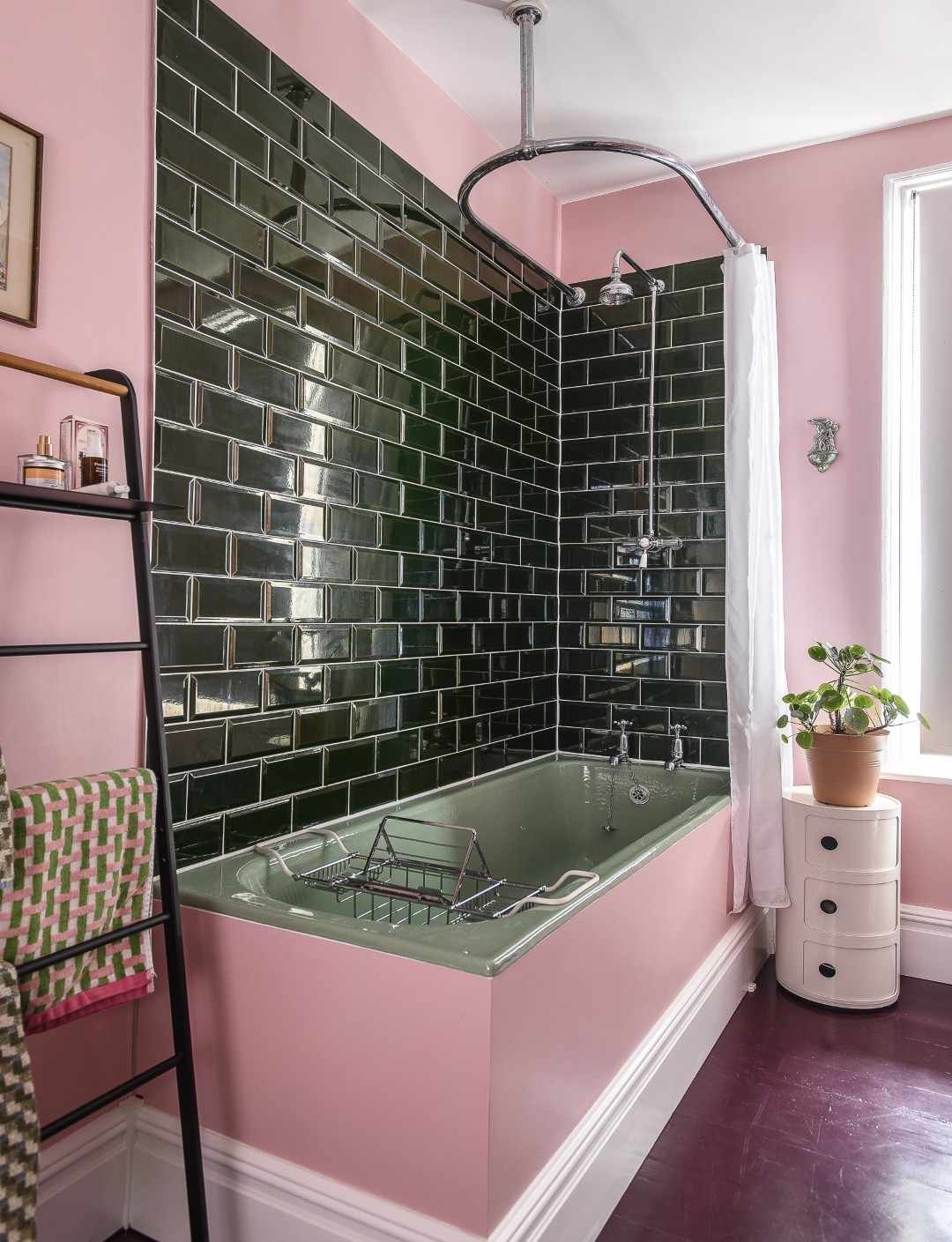 The bathroom walls are painted Farrow & Ball’s Nancy’s Blushes, and the floor in Dulux Kidney Bean. Green tiles complement the vintage green bath and pedestal sink