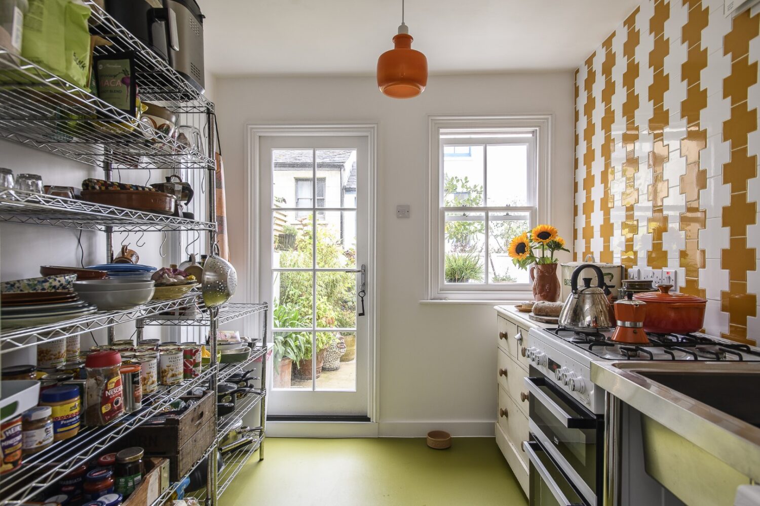 The galley kitchen is tiled in mustard and white Spanish-style geometric ceramics.