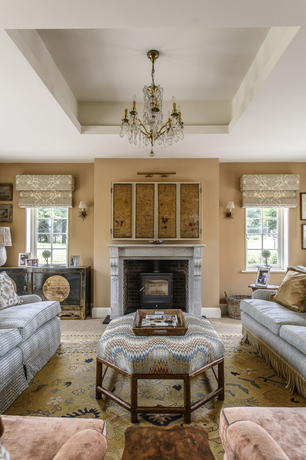 The TV, mounted above the fireplace, is now cleverly concealed – “We hid it behind folding Chinoiserie glass panels with a picture light above. It now looks like artwork. When you fold the panels back to reveal the TV, it still looks beautiful.”