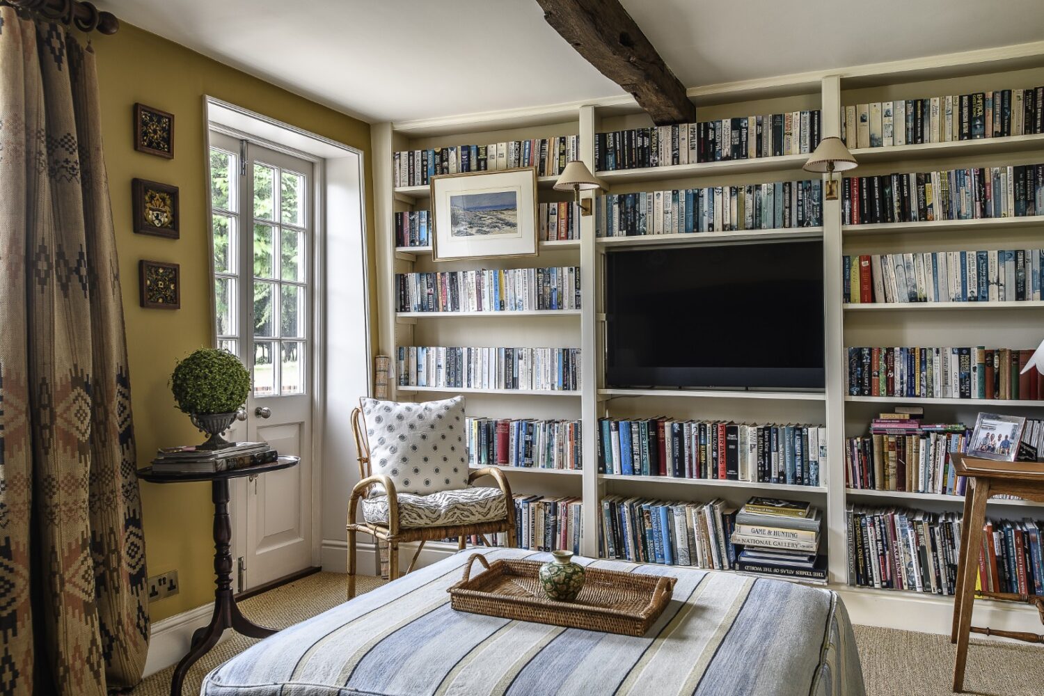 The colour scheme was inspired by a pair of antique Swedish curtains. Warm yellow, darkened with accents of black, is softened with bookshelves and old Hungarian plates hung on the wall