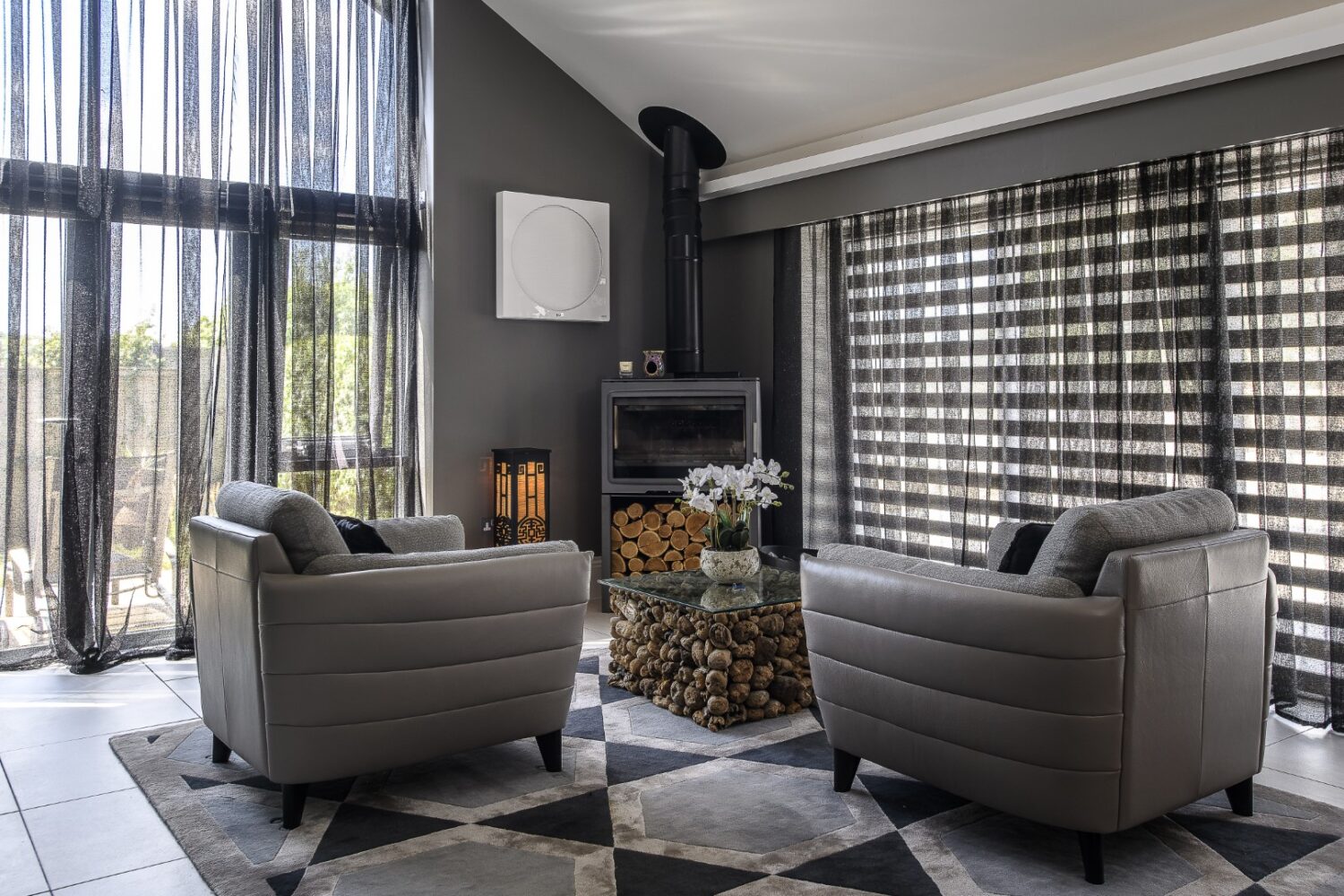 The principal bedroom is dramatic in scale. A four-poster bed stands against upholstered panelling, with a log-burning stove in the corner for winter nights.