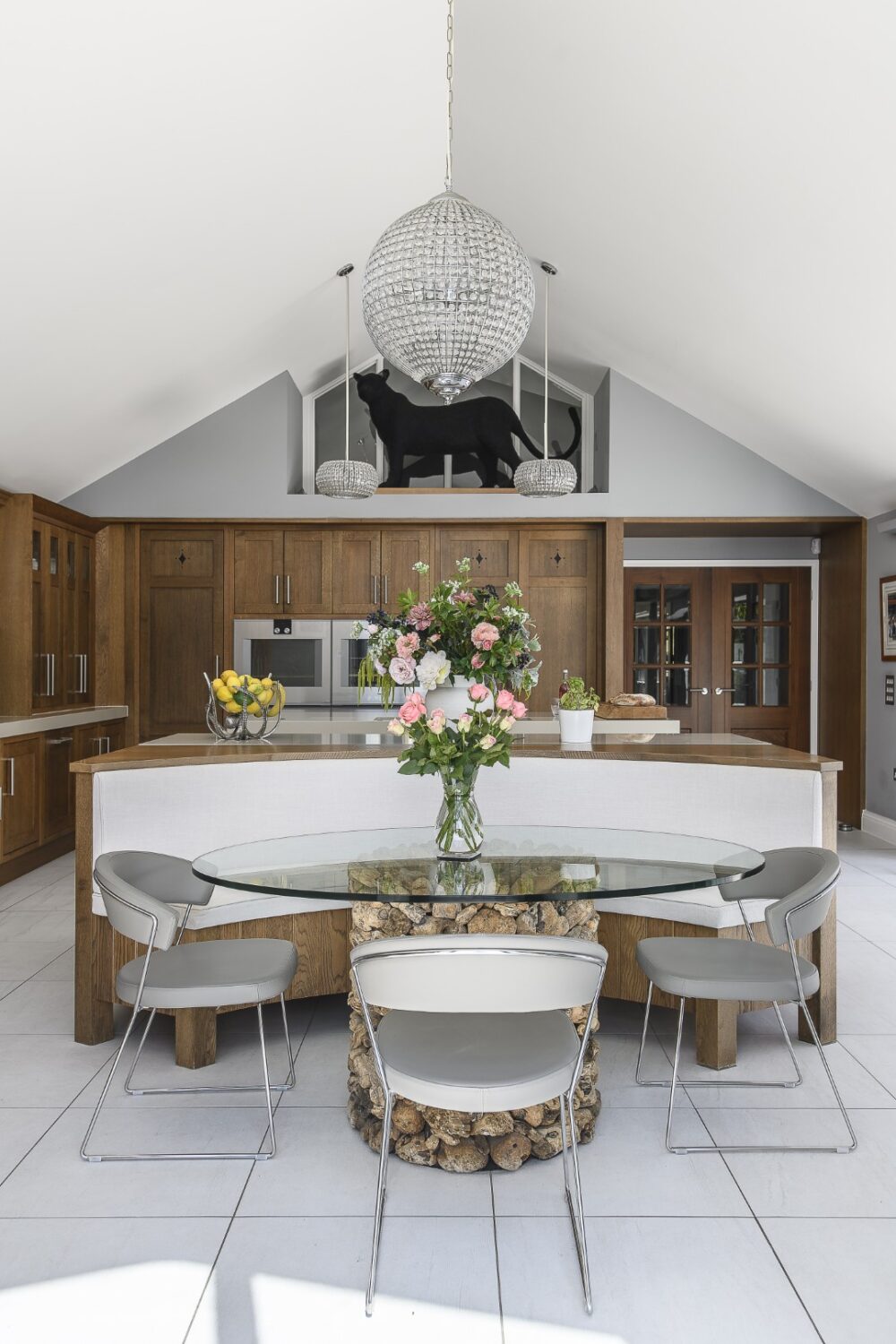 In the kitchen twin islands stretch out under glittering pendant lights, worktops provide plenty of space for cooking and huge windows connect directly to the terrace outside.