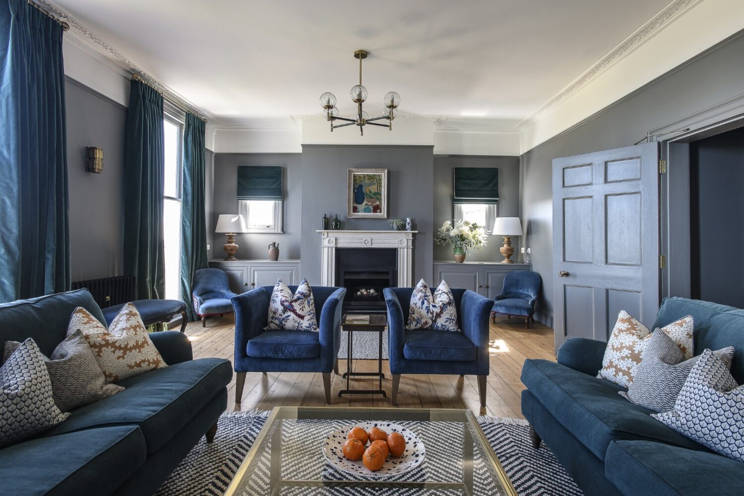 The drawing room, in shades of deep grey and navy, spans across the back of the house on the first floor and is flooded with coastal light