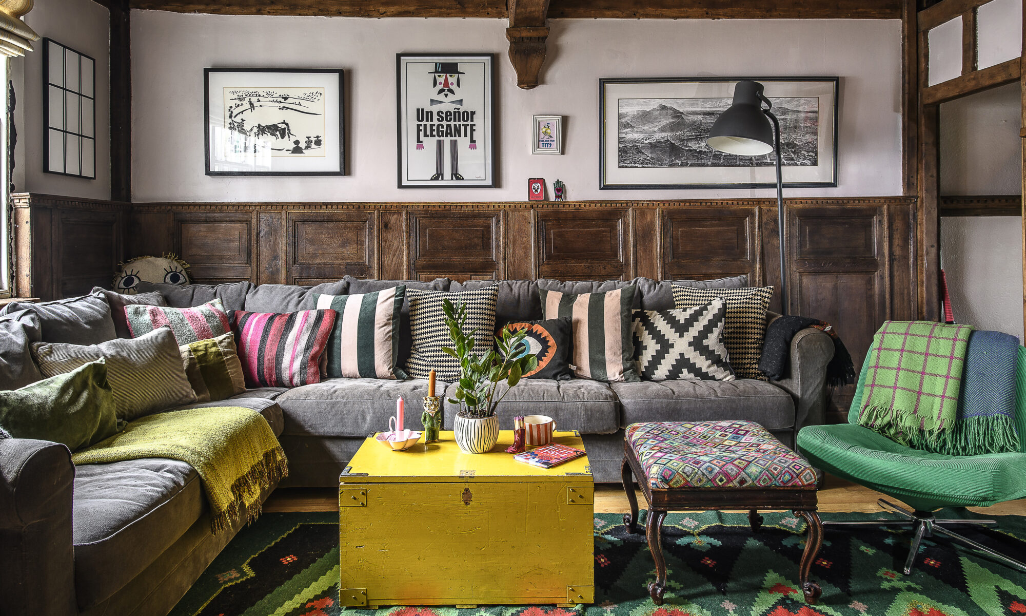 The sitting room is brightened with striped cushions and woven kilims in bold rainbow hues. The walls are hung with a mix of graphic prints alongside vintage finds and family mementoes