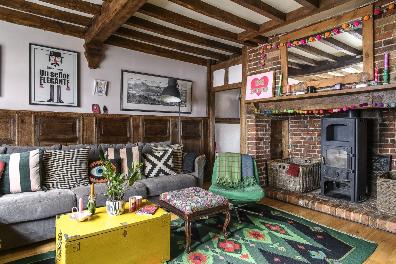 The panelled living room is home to a big inglenook fireplace, home to a ‘Be Kind’ print by Dandy