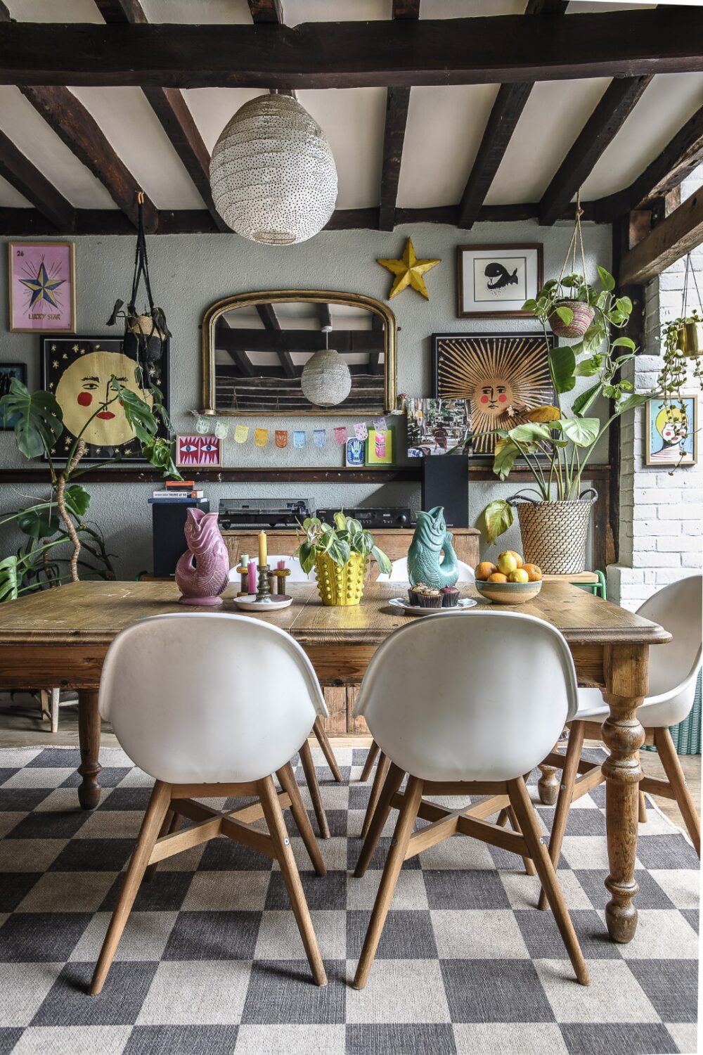 The well-loved pine dining table is surrounded by contemporary dining chairs from Ikea, bright artwork by the likes of Tabby Booth and Samantha Stas, and houseplants. A set of turntables on the sideboard nod to the family’s love of music