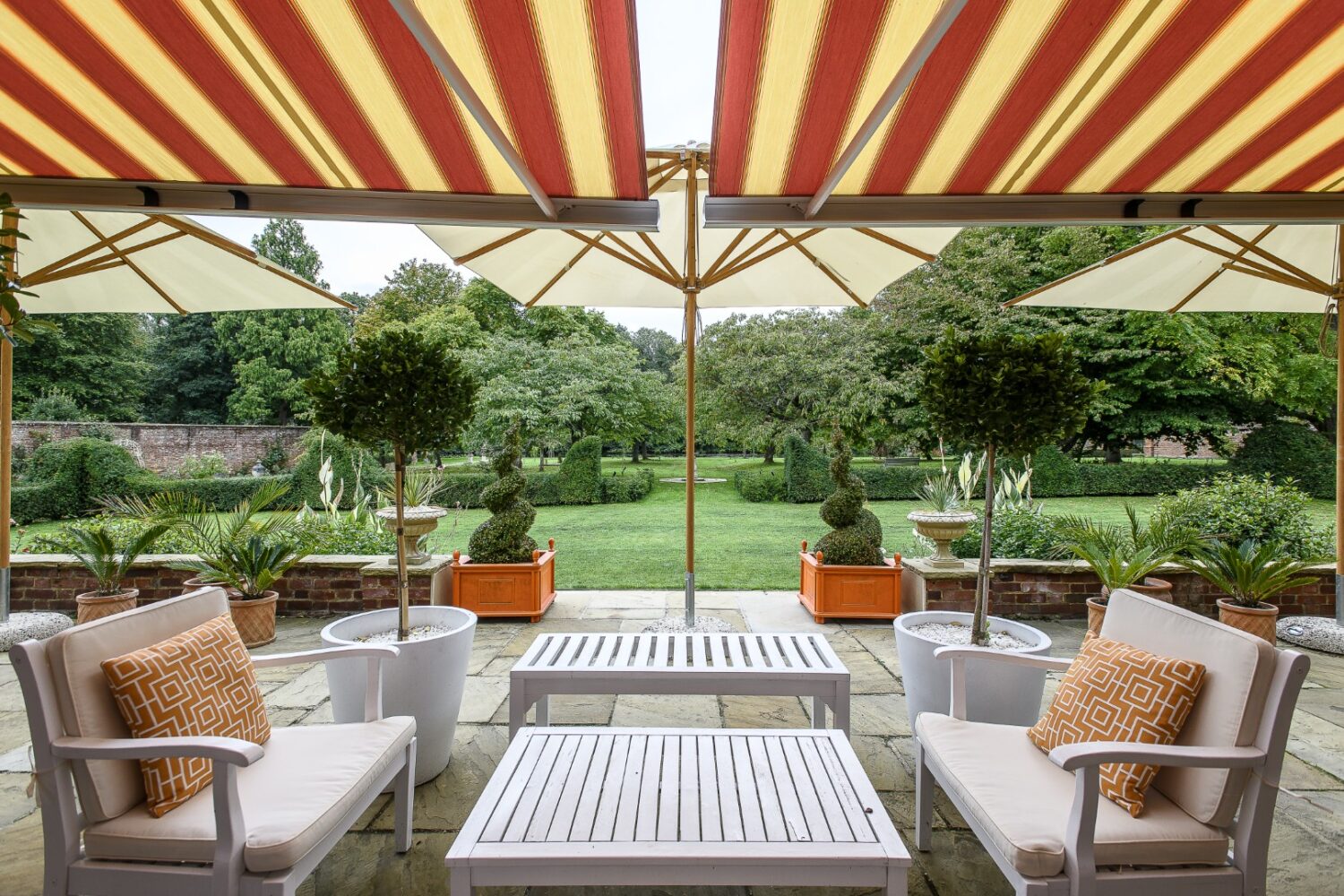 Striped awnings and Mediterranean furnishings lend a holiday feel to the terrace that wraps around the main house
